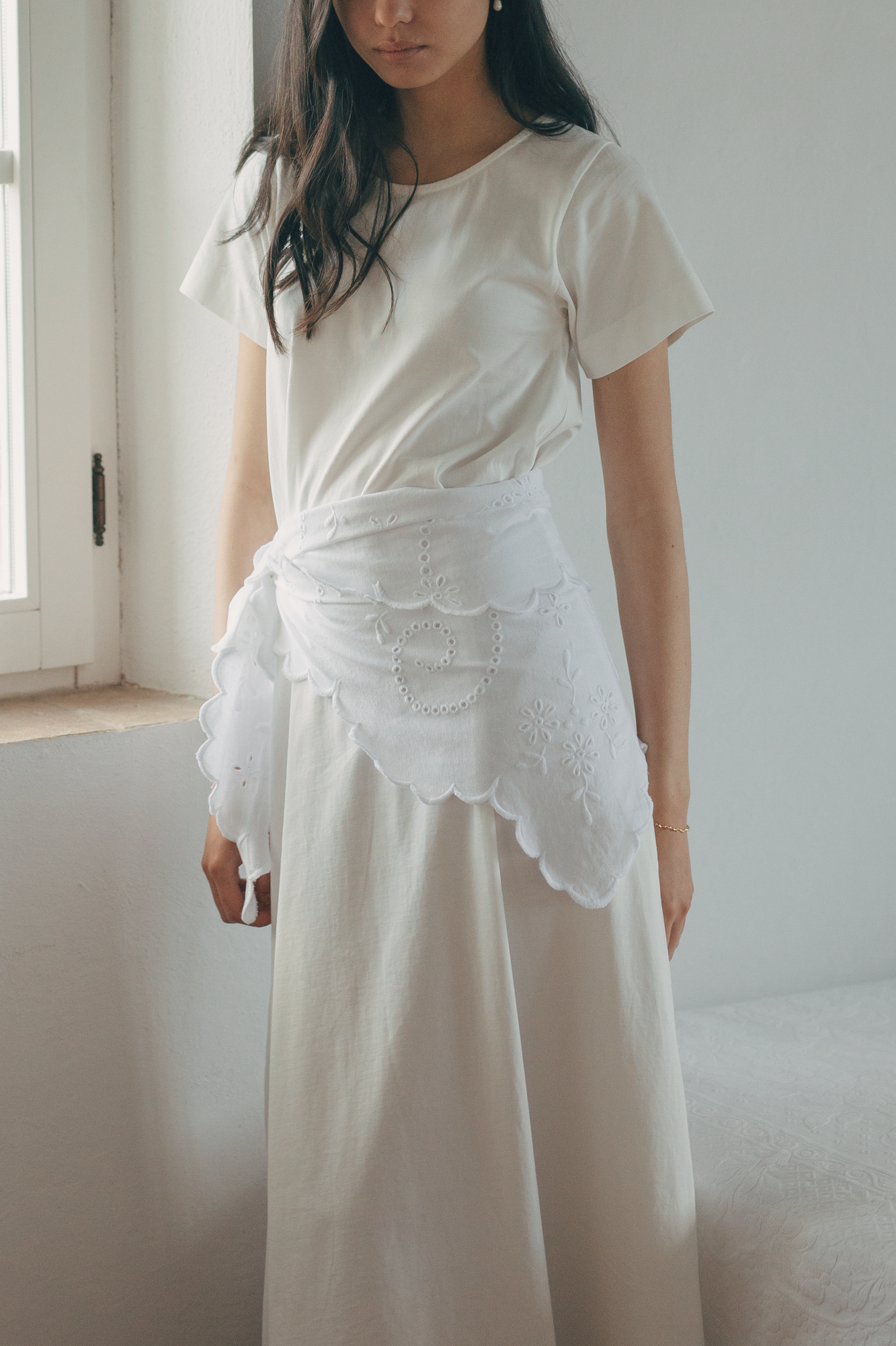 Model wearing the Matilde Scarf in Salt by Gillian Stevens, tied at the waist over a maxi skirt, showing broderie detail
