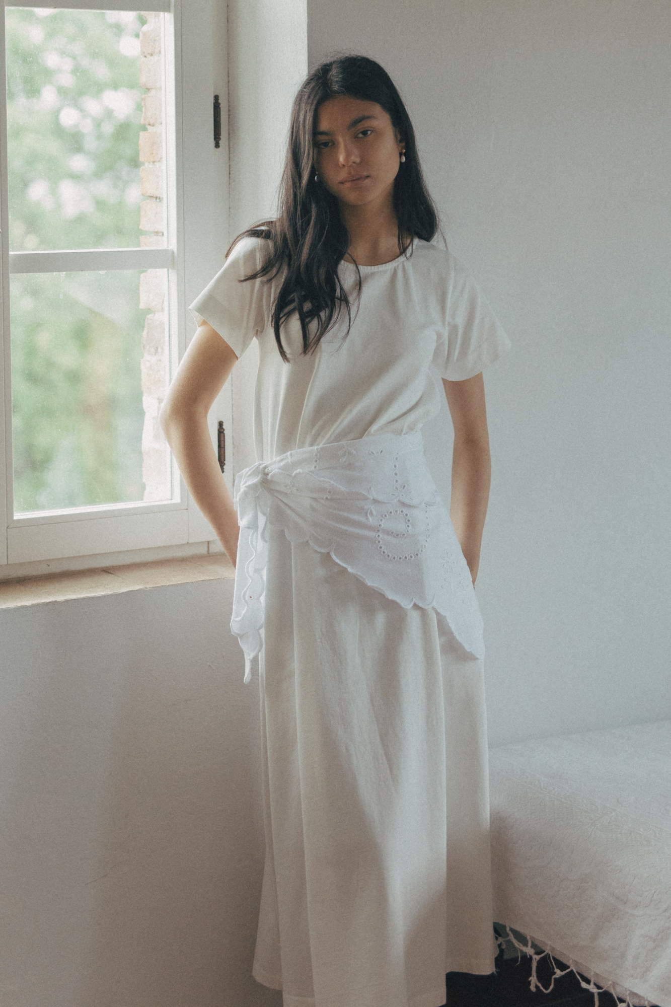 Model wearing the Matilde Scarf in Salt by Gillian Stevens, tied at the waist over a white dress, front view