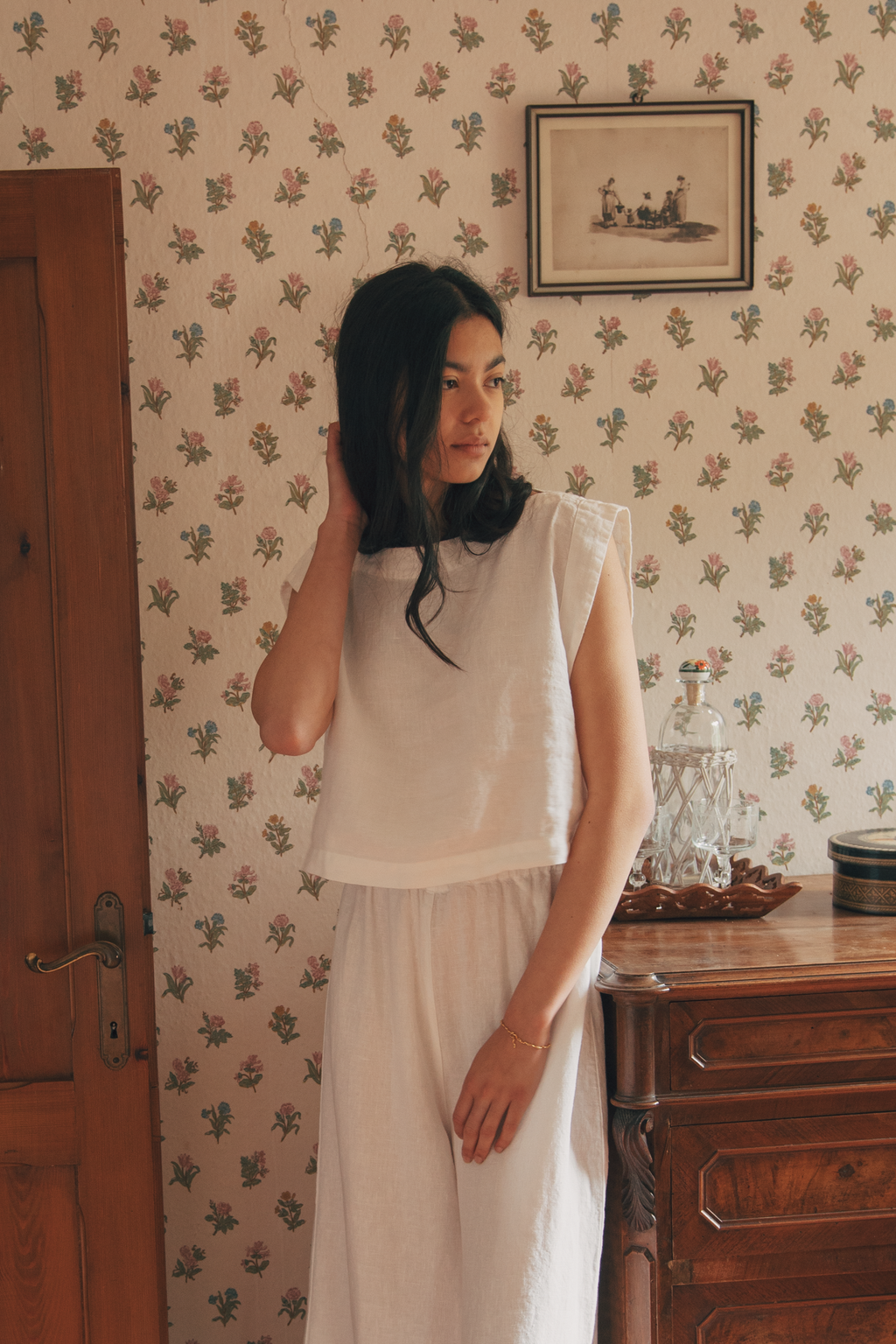 Model wearing the Valley Top in Salt by Gillian Stevens, three-quarter view styled with wide-leg trousers in a vintage room