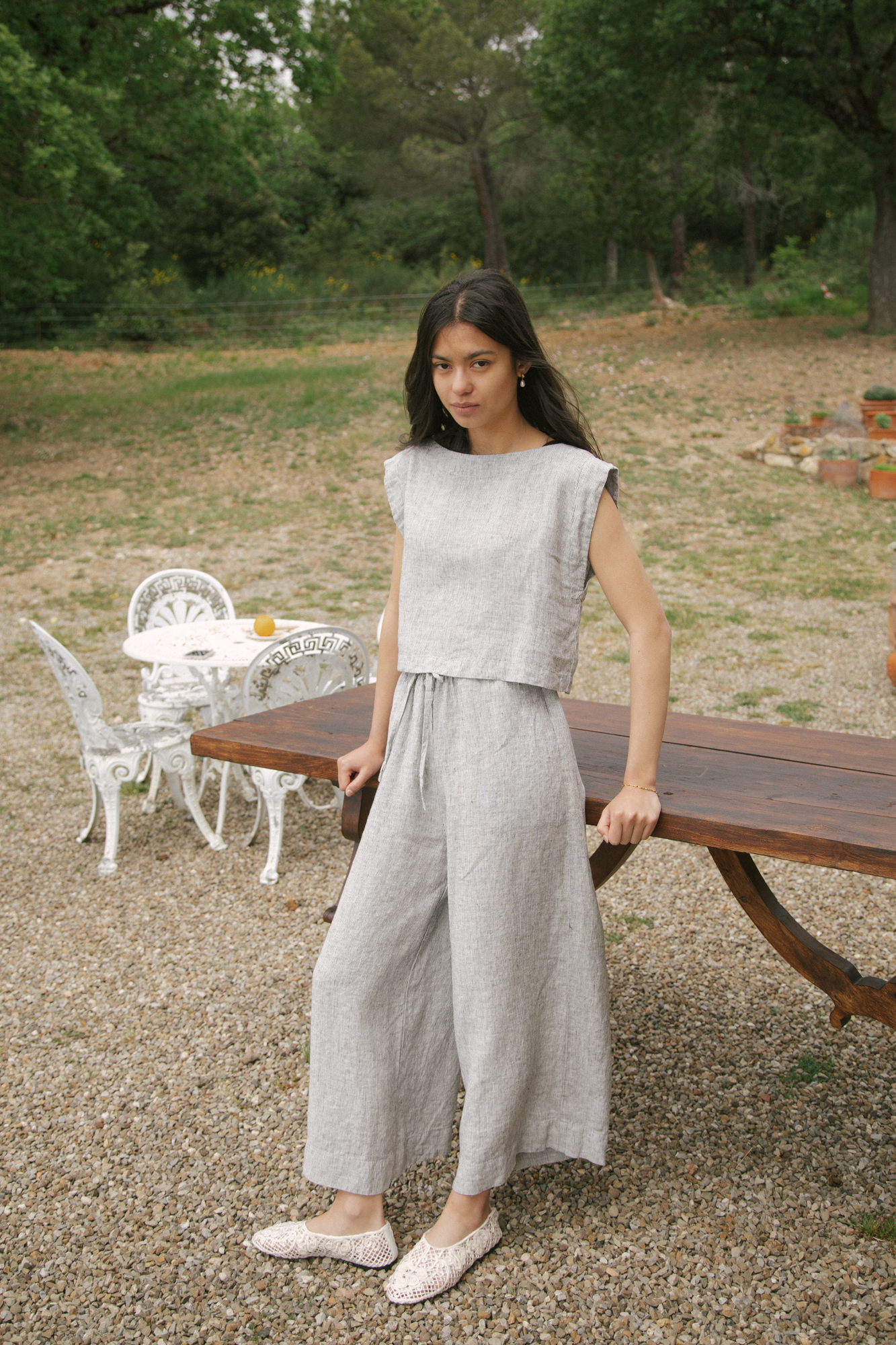 Model wearing the Ines Pant in Charcoal Stripe by Gillian Stevens, full-length front view in an outdoor garden setting