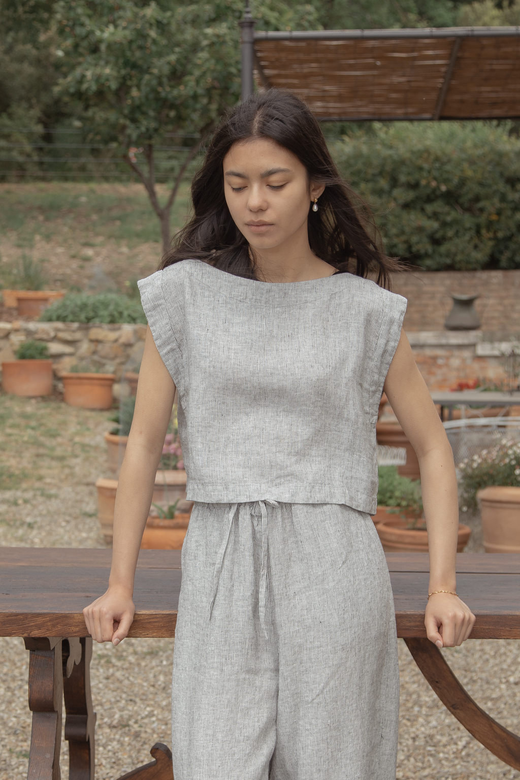 Model wearing the Valley Top in Charcoal Stripe by Gillian Stevens, front view in an outdoor garden setting