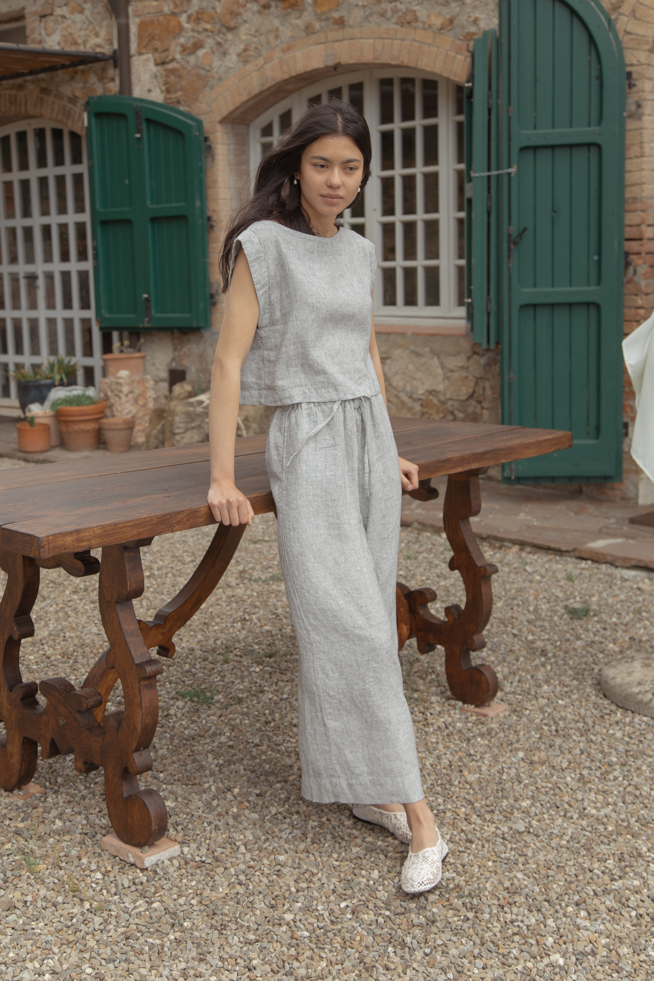 Model wearing the Ines Pant in Charcoal Stripe by Gillian Stevens, front view in a rustic outdoor setting