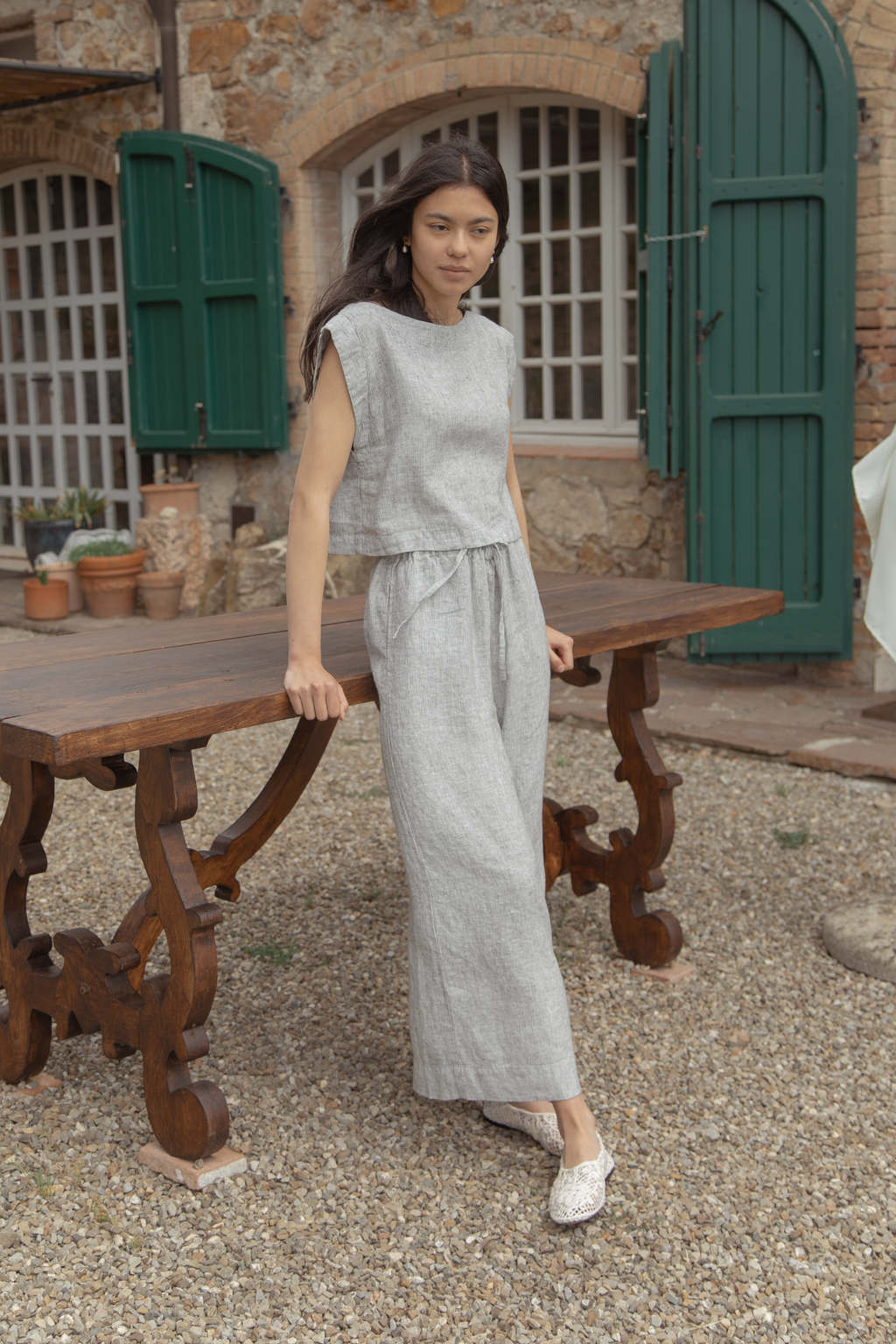 Model wearing the Valley Top in Charcoal Stripe by Gillian Stevens, front view styled with matching linen trousers outdoors