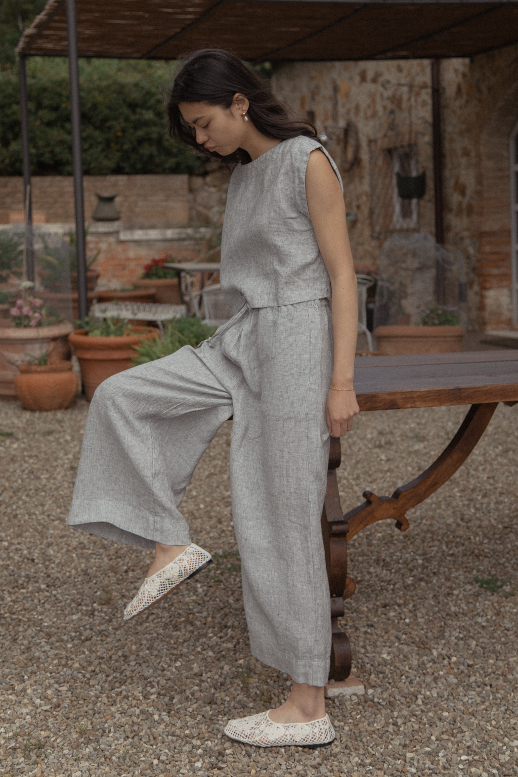 Model wearing the Valley Top in Charcoal Stripe by Gillian Stevens, side view styled with wide-leg pants outdoors