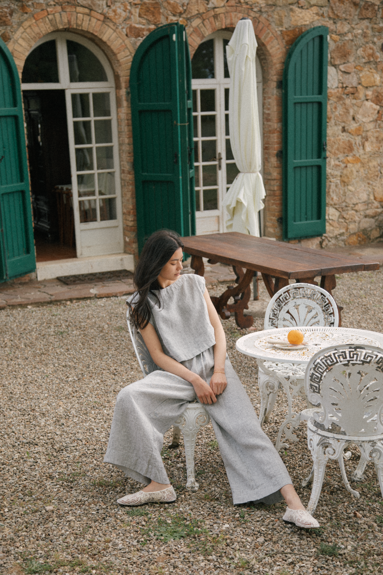 Model seated outdoors in the Ines Pant Charcoal Stripe by Gillian Stevens, paired with a matching top