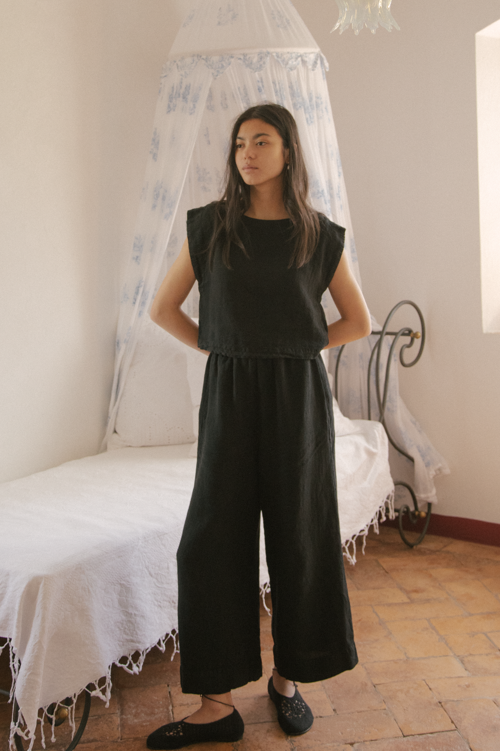 Model wearing the Valley Top in Noir by Gillian Stevens, full-length front view styled with wide-leg pants