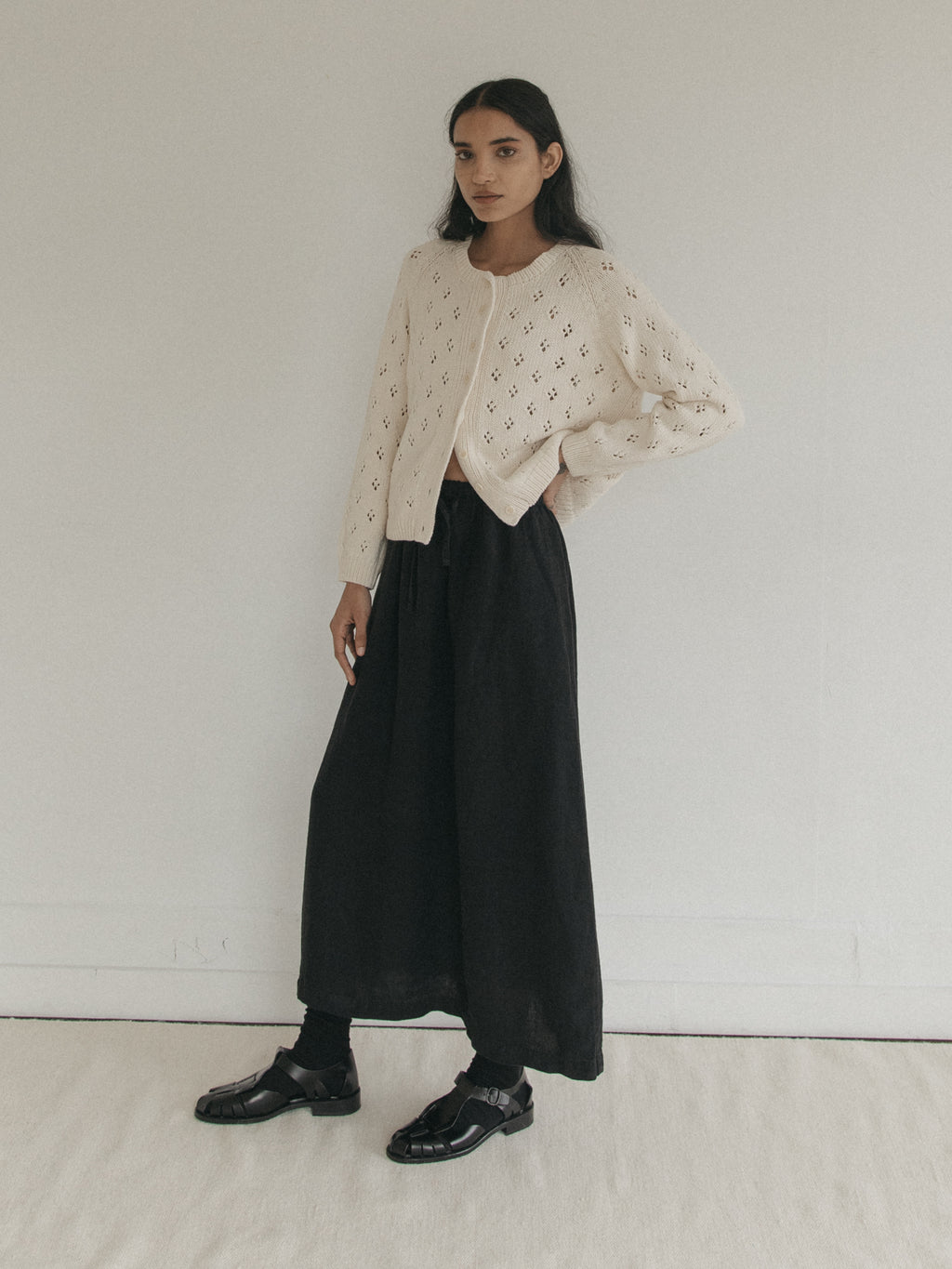 Model wearing the Mabel Cardigan in Ivory by Gillian Stevens, full-length front view with black midi skirt