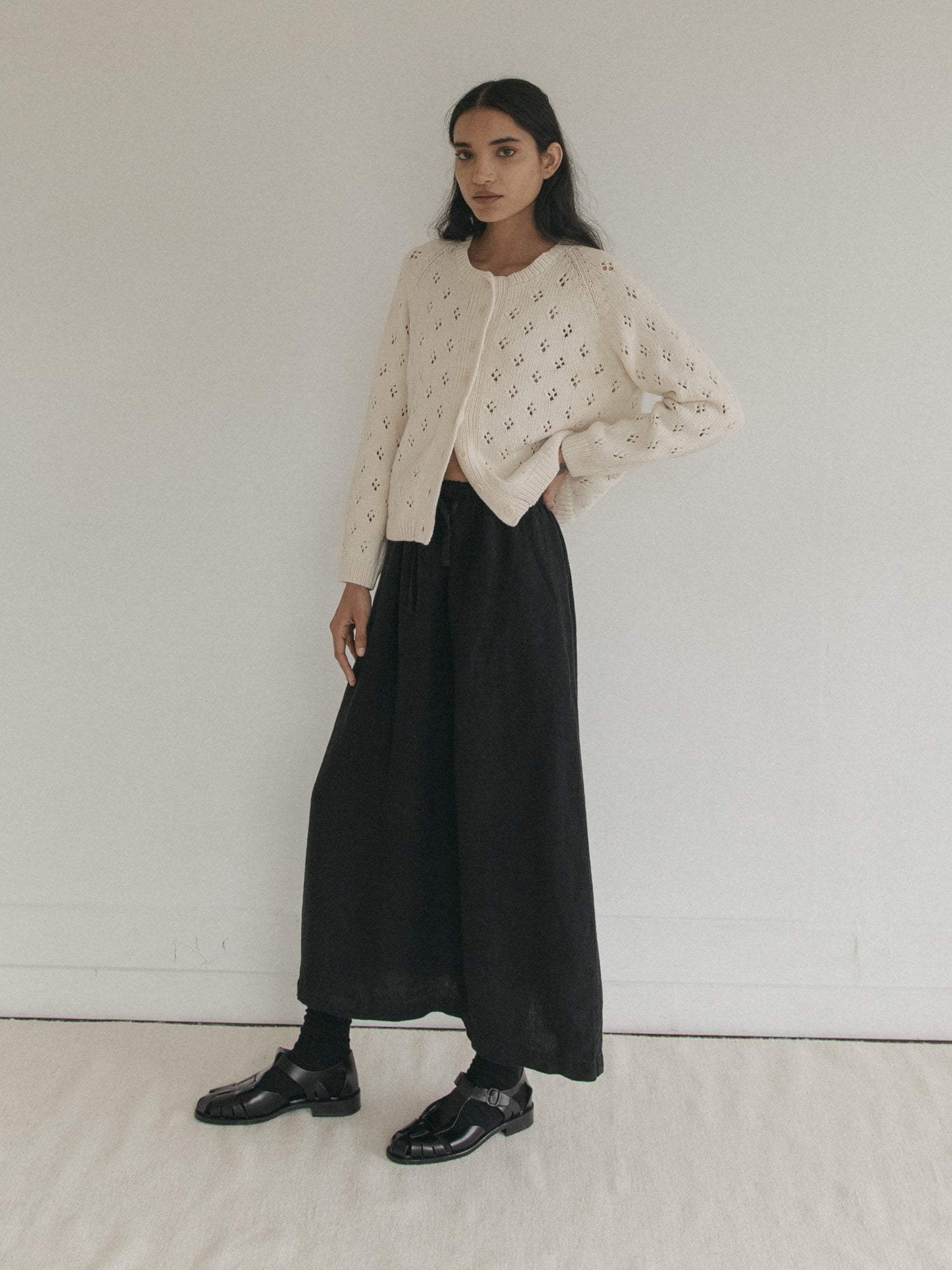 Model wearing the Mabel Cardigan in Ivory by Gillian Stevens, full-length front view with black midi skirt