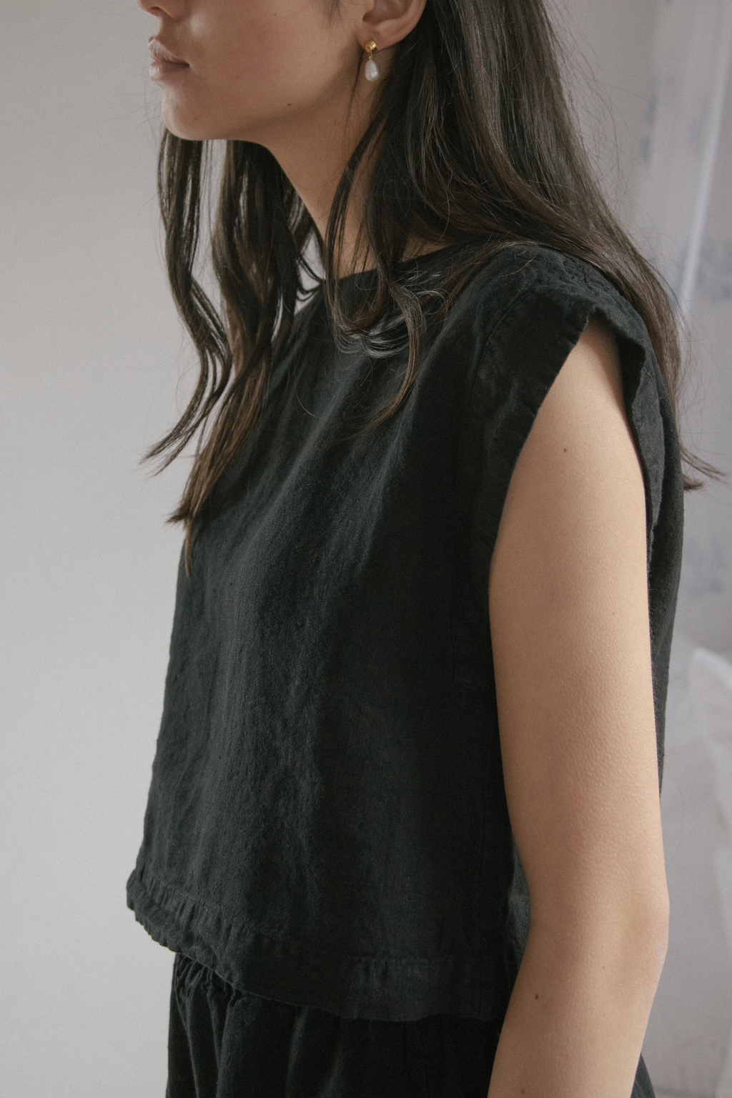 Model wearing the Valley Top in Noir by Gillian Stevens, close-up side view showing frill hem detail