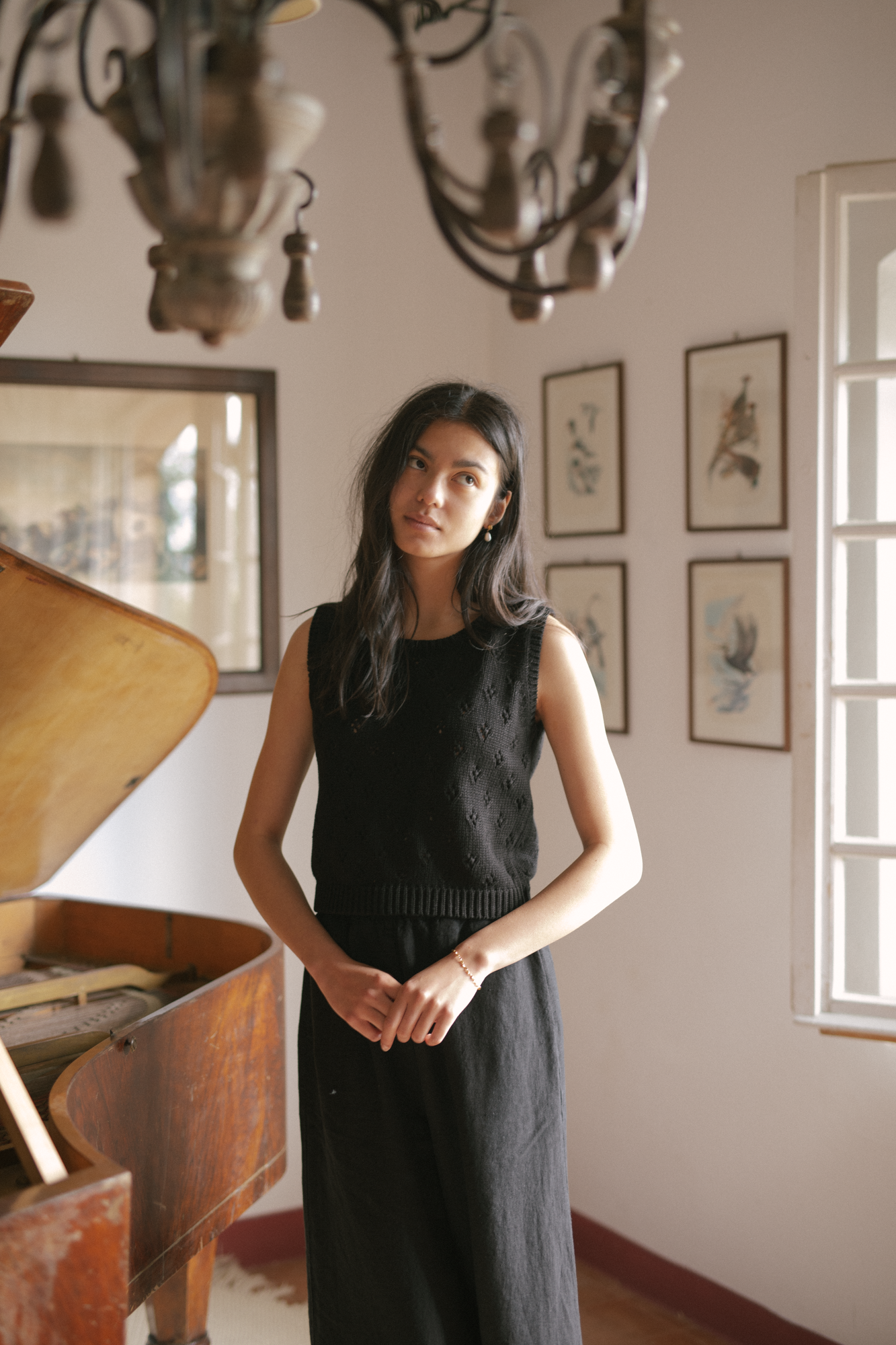 Model wearing the Niah Top in Noir by Gillian Stevens, front view styled with wide-leg trousers in a vintage interior