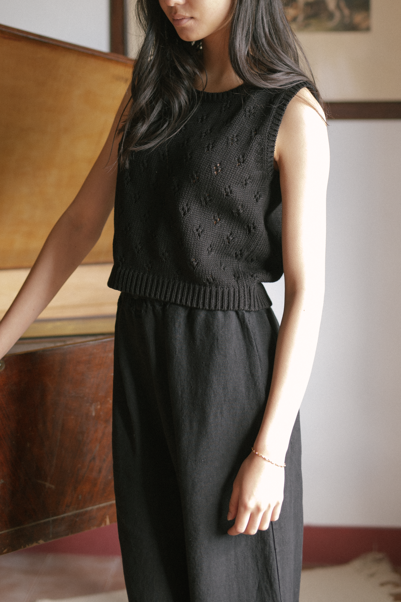 Model wearing the Niah Top in Noir by Gillian Stevens, cropped front view showing pointelle knit detail and ribbed hem