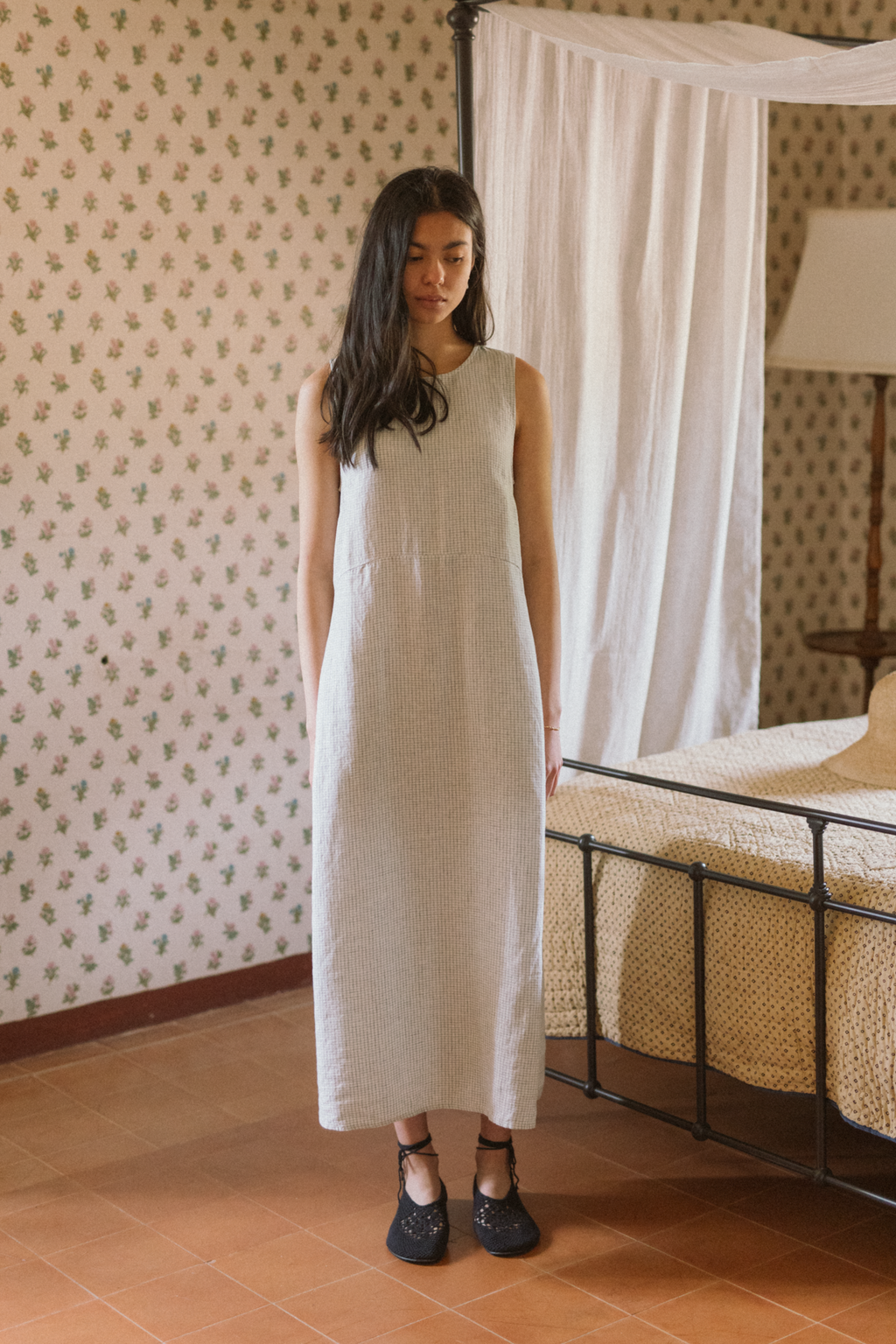 Model wearing the Paige Dress in Dusty Blue Plaid by Gillian Stevens, front view in a vintage bedroom setting