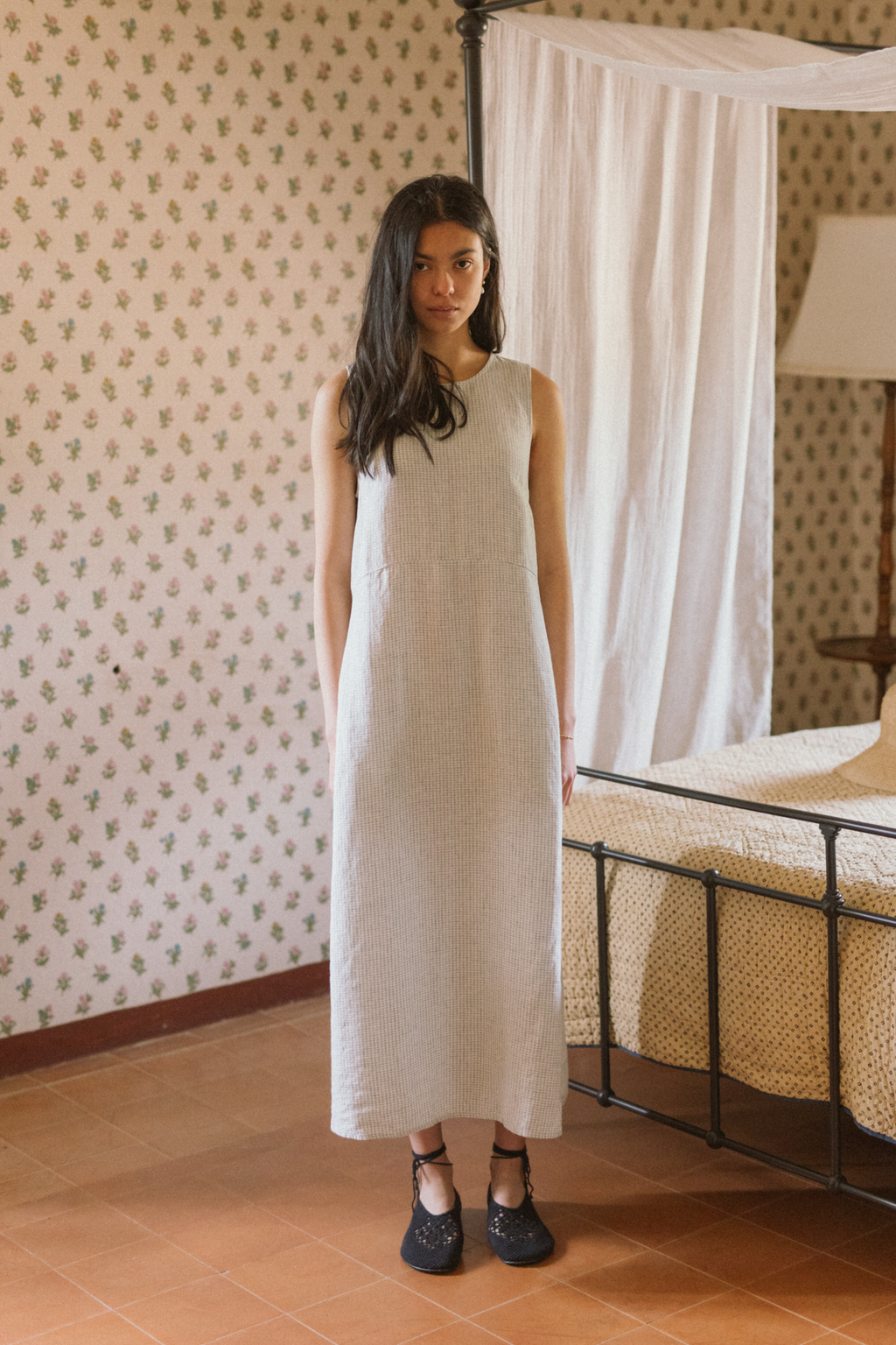 Model wearing the Paige Dress in Dusty Blue Plaid by Gillian Stevens, front view in a vintage bedroom setting