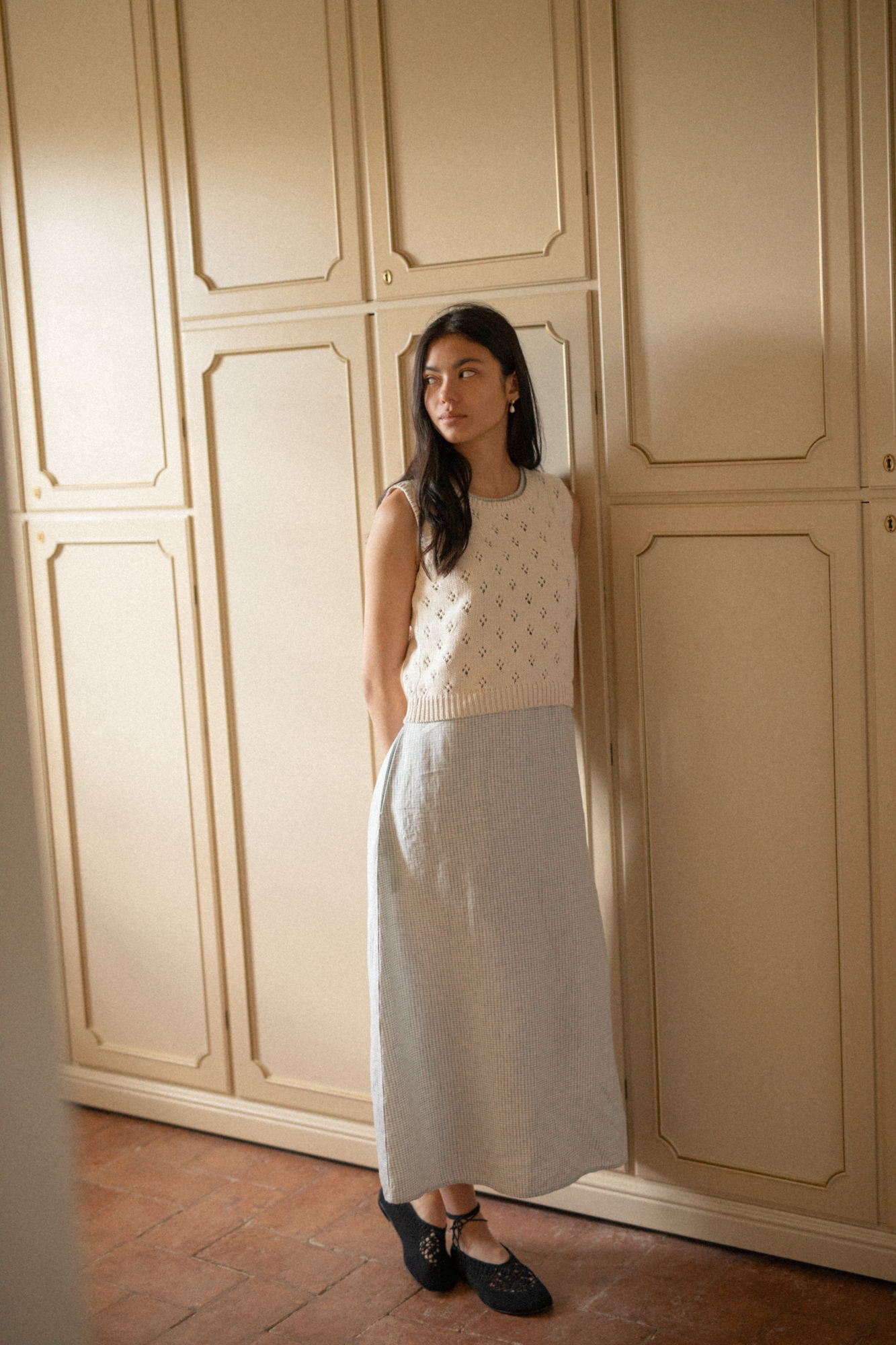 Model wearing the Niah Top in Ivory by Gillian Stevens, full-length side view styled with a midi skirt