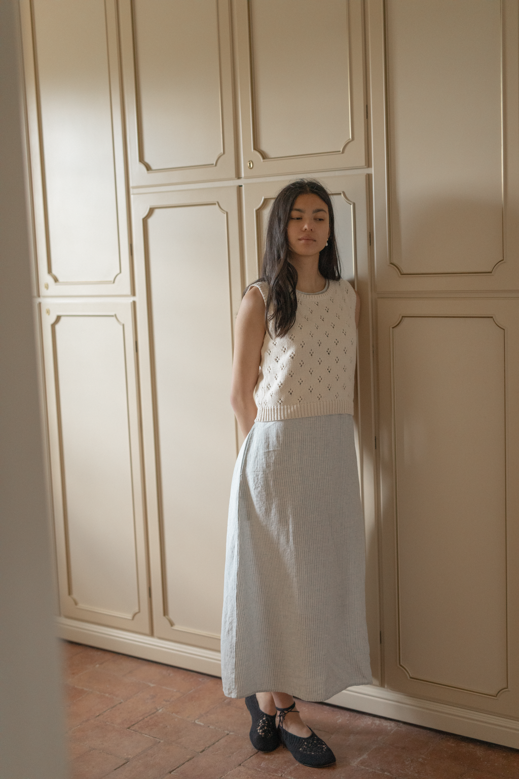 Model wearing the Niah Top in Ivory by Gillian Stevens, full-length front view styled with a midi skirt