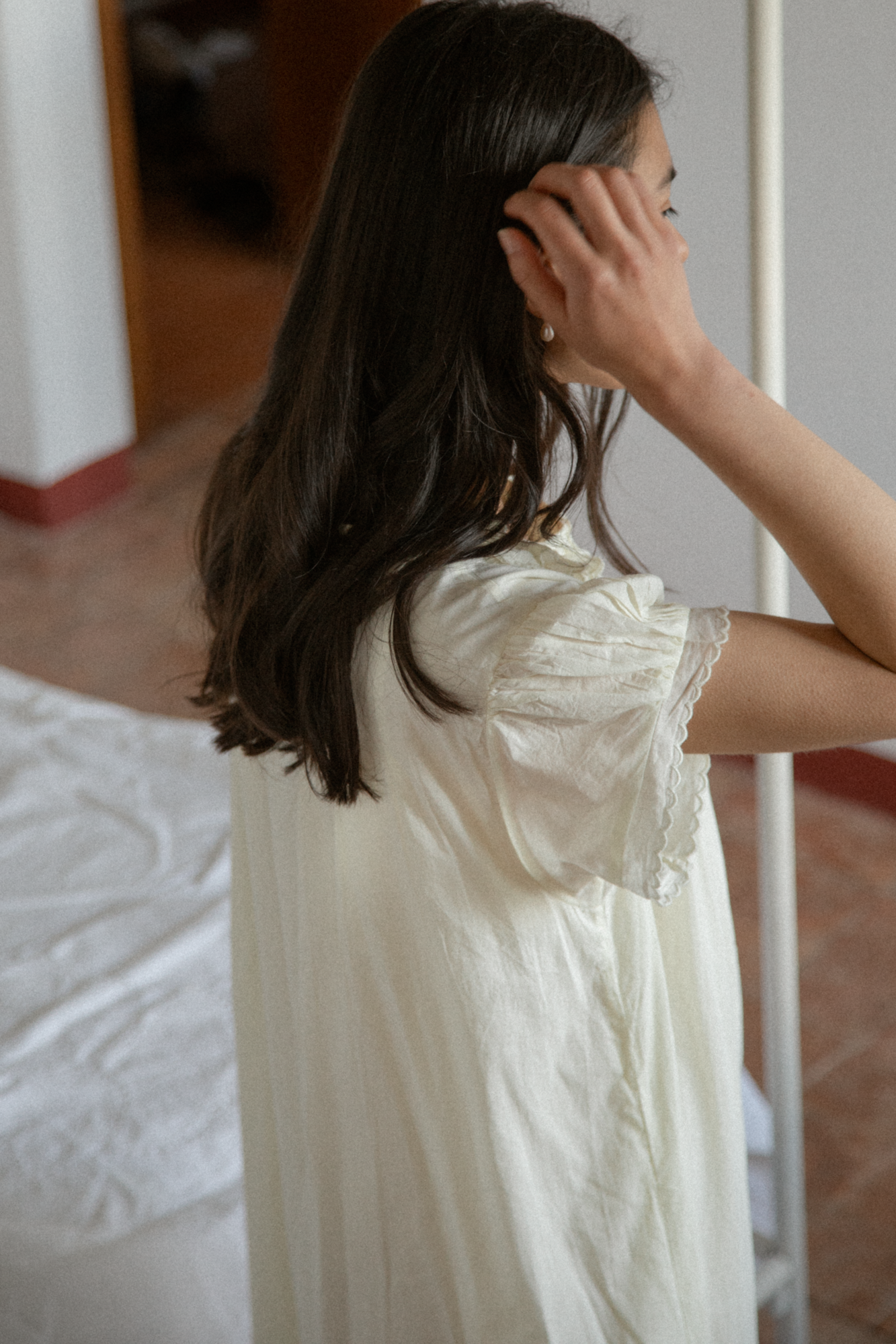 Model wearing the Clover Dress in Butter by Gillian Stevens, back view showing lace-trimmed flutter sleeve