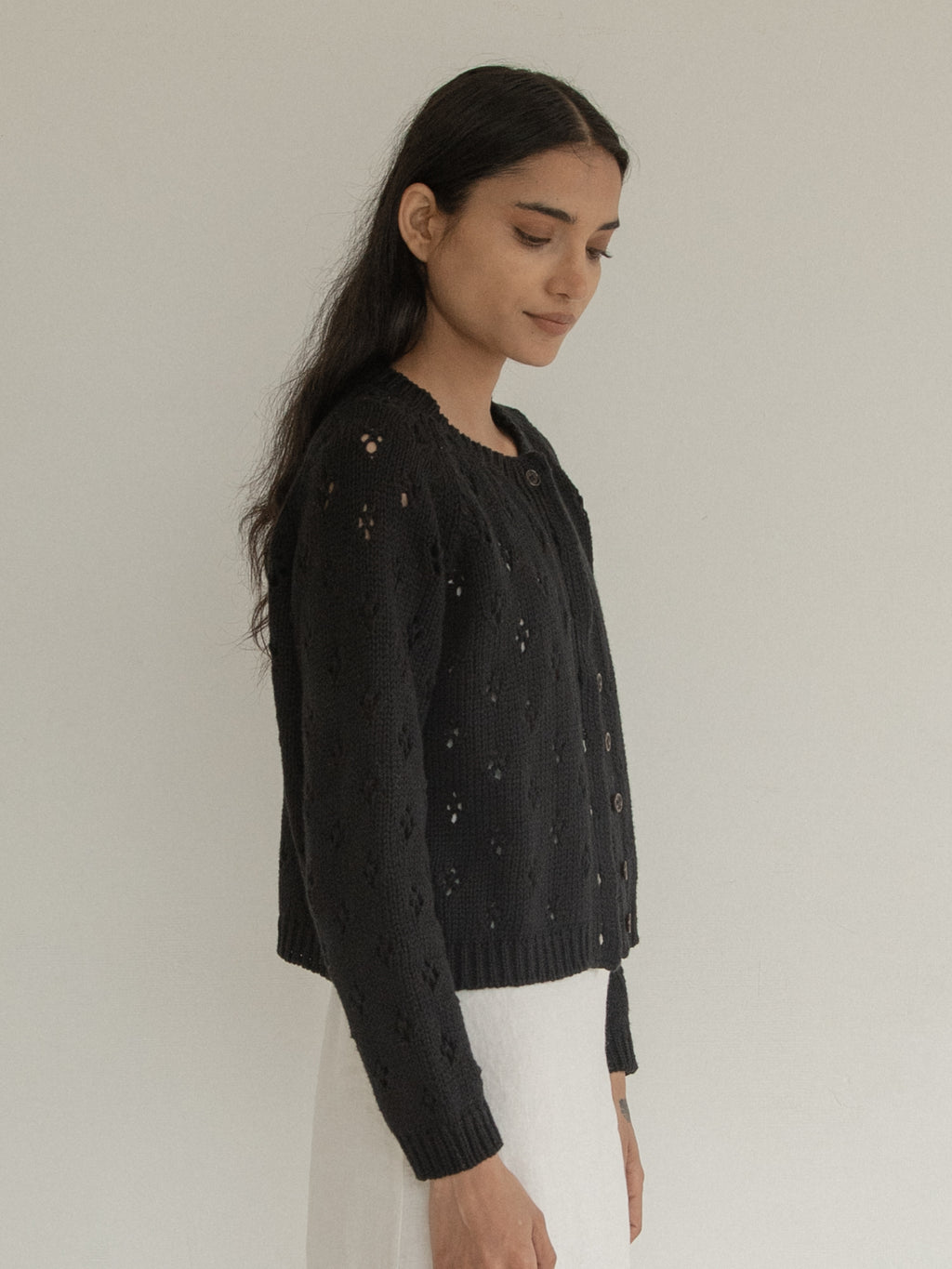 Model wearing the Mabel Cardigan in Noir by Gillian Stevens, side view showing floral eyelet detail