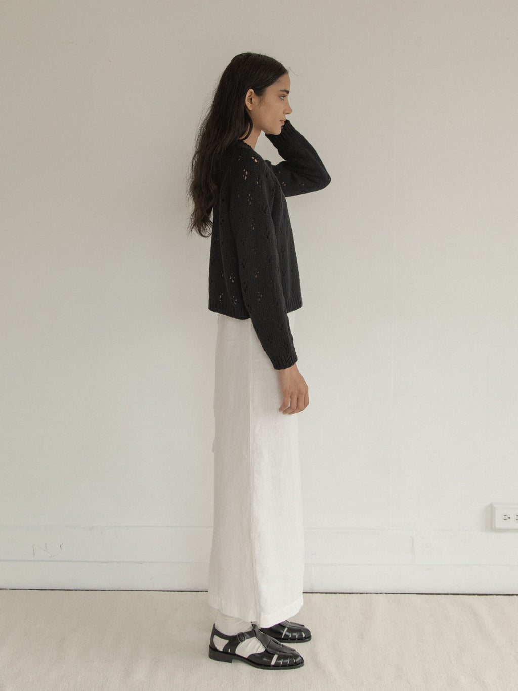 Model wearing the Mabel Cardigan in Noir by Gillian Stevens, side view showing open-knit texture