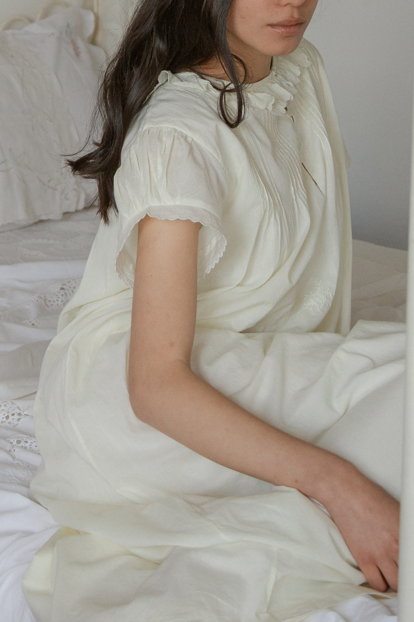 Model seated wearing the Clover Dress in Butter by Gillian Stevens, side view showing pintuck detail and scalloped sleeves
