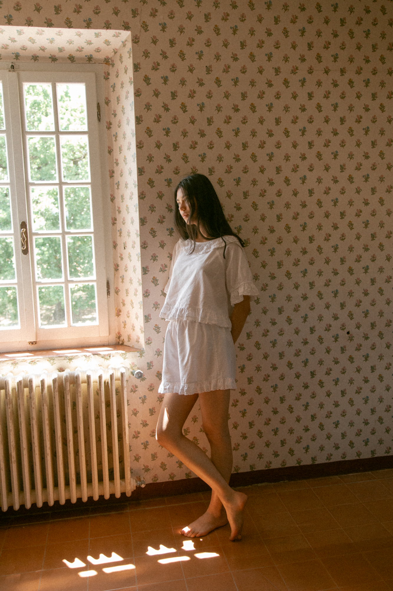 Model wearing the Arlette Short in Salt by Gillian Stevens, full-length side view in a sunlit room