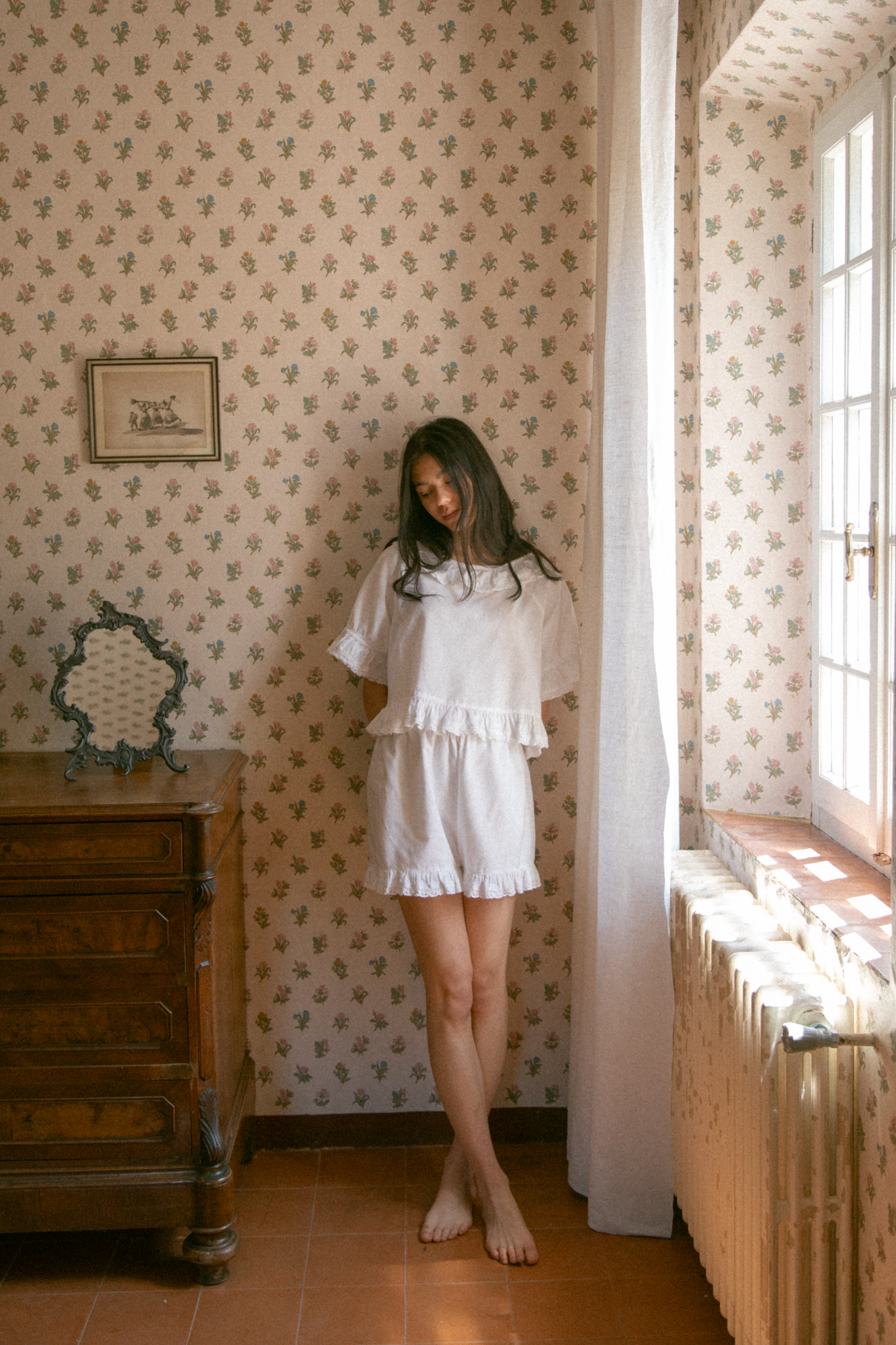 Model wearing the Arlette Short in Salt by Gillian Stevens, front view in a vintage floral room by a window