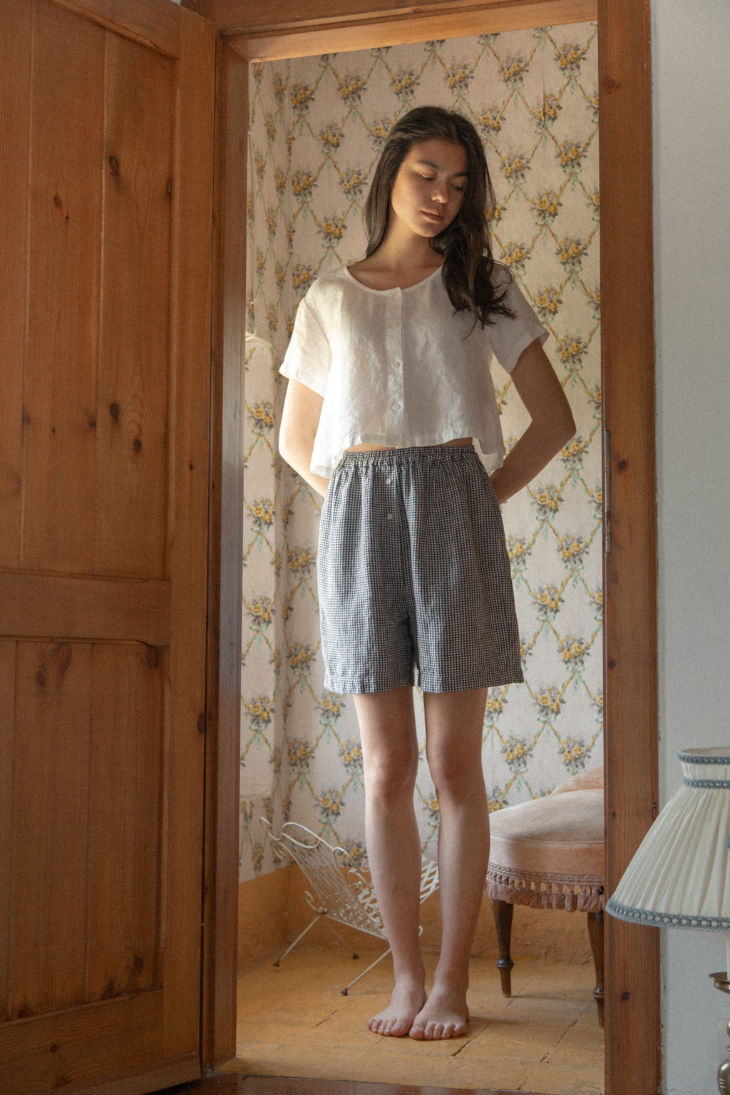 Model wearing the Wren Top in Salt by Gillian Stevens, front view styled with gingham shorts in a vintage room