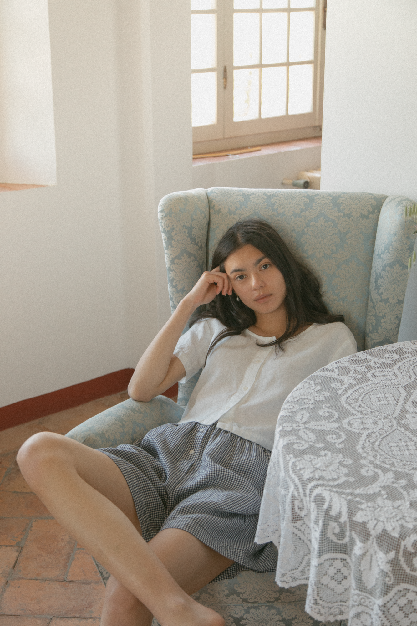 Model seated in a vintage armchair wearing the Wren Top in Salt by Gillian Stevens, relaxed front view