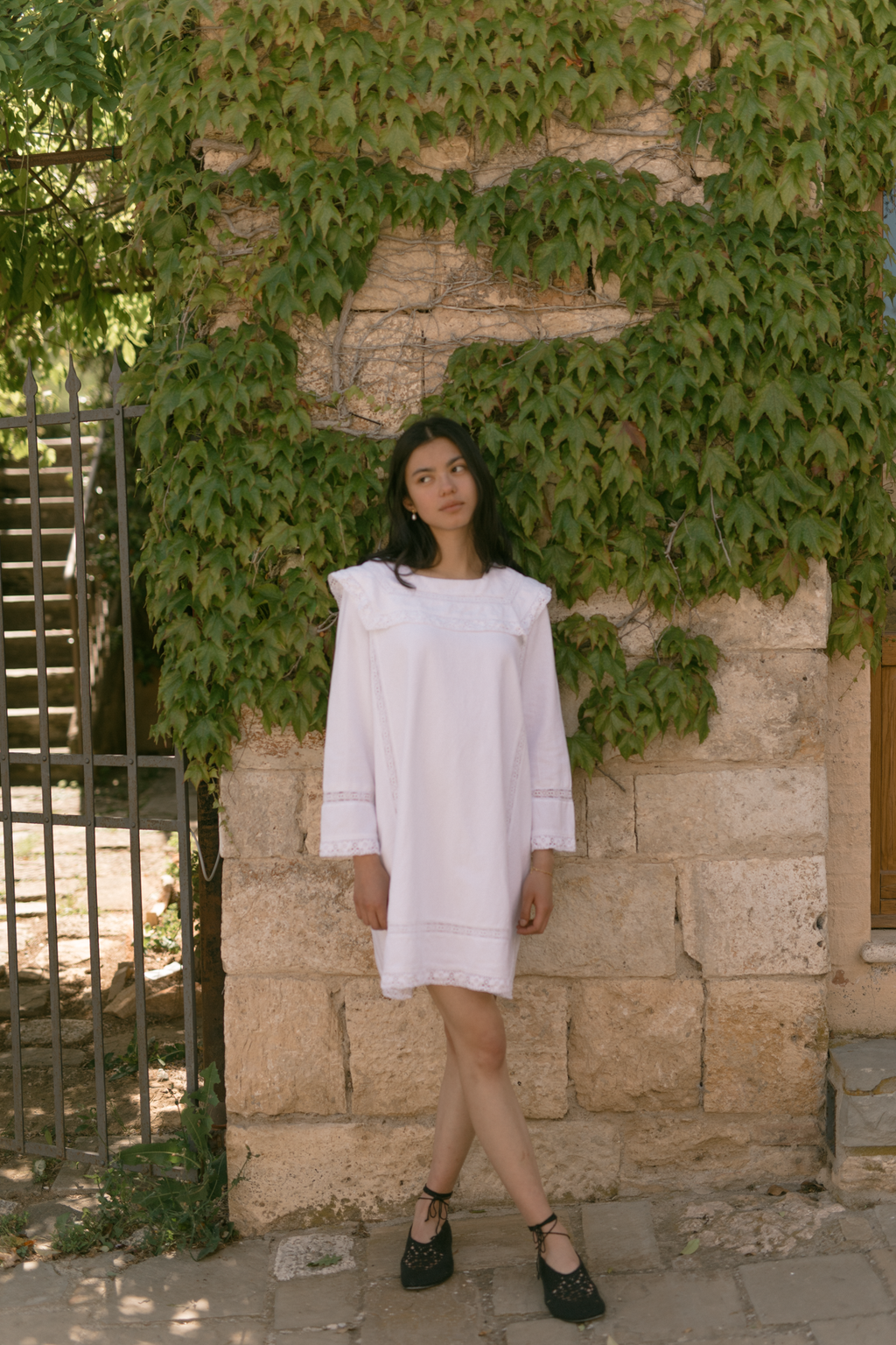 Model in the Laine Dress in Salt by Gillian Stevens, full-length front view against an ivy-covered stone wall