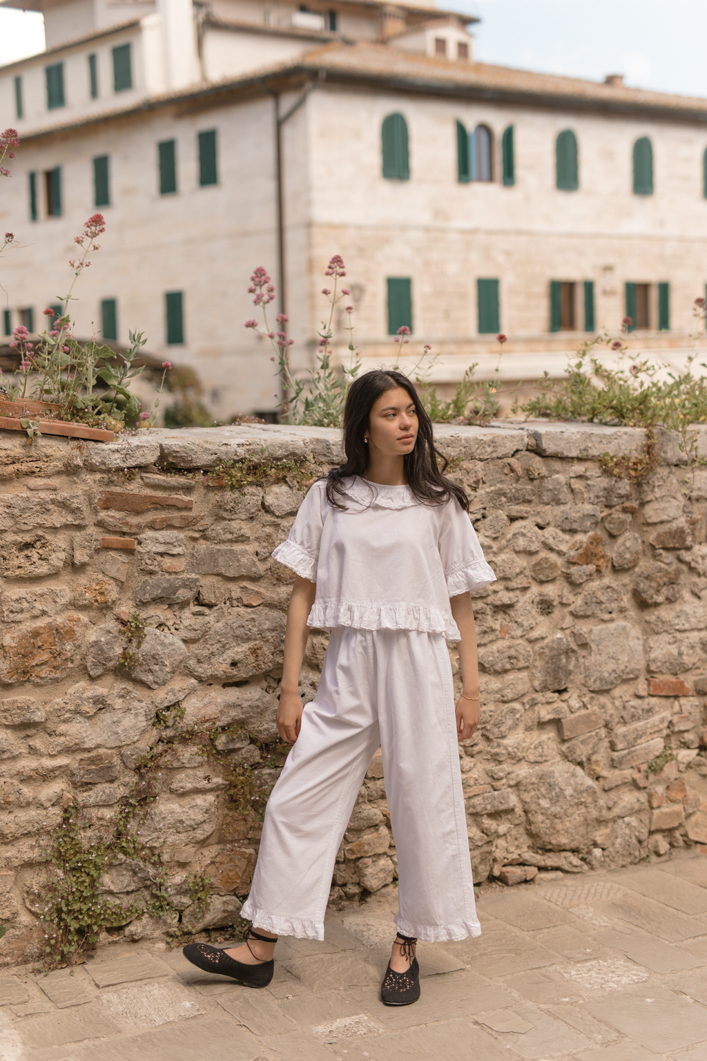 Model wearing the Arlette Pant in Salt by Gillian Stevens, full-length front view against a stone wall
