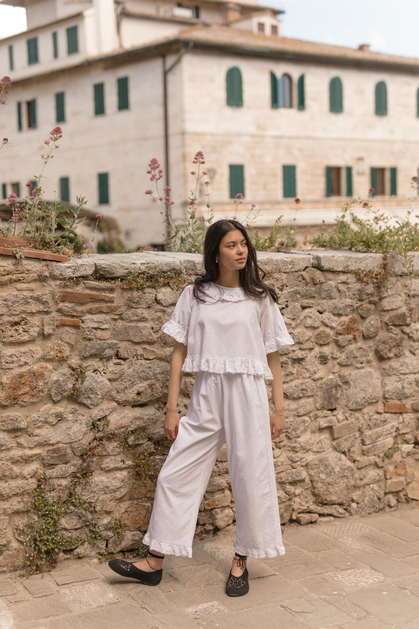 Model wearing the Arlette Pant in Salt by Gillian Stevens, full-length front view against a stone wall