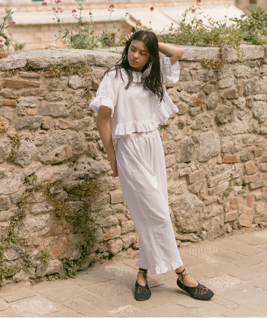 Model wearing the Arlette Pant in Salt by Gillian Stevens, full-length front view against a stone wall