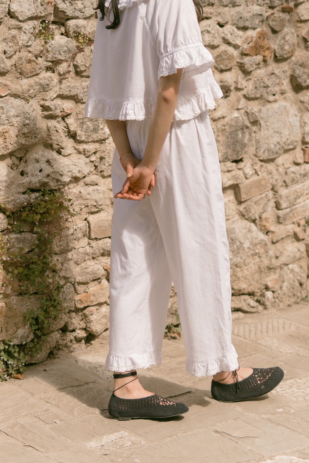 Model wearing the Arlette Pant in Salt by Gillian Stevens, side view showing lace hem detail