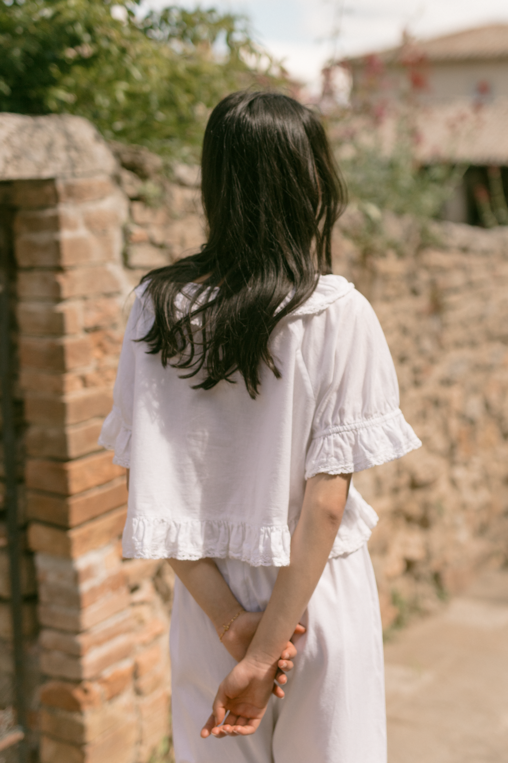Model wearing the Arlette Top in Salt by Gillian Stevens, back view showing ruffle hem and sleeve detail