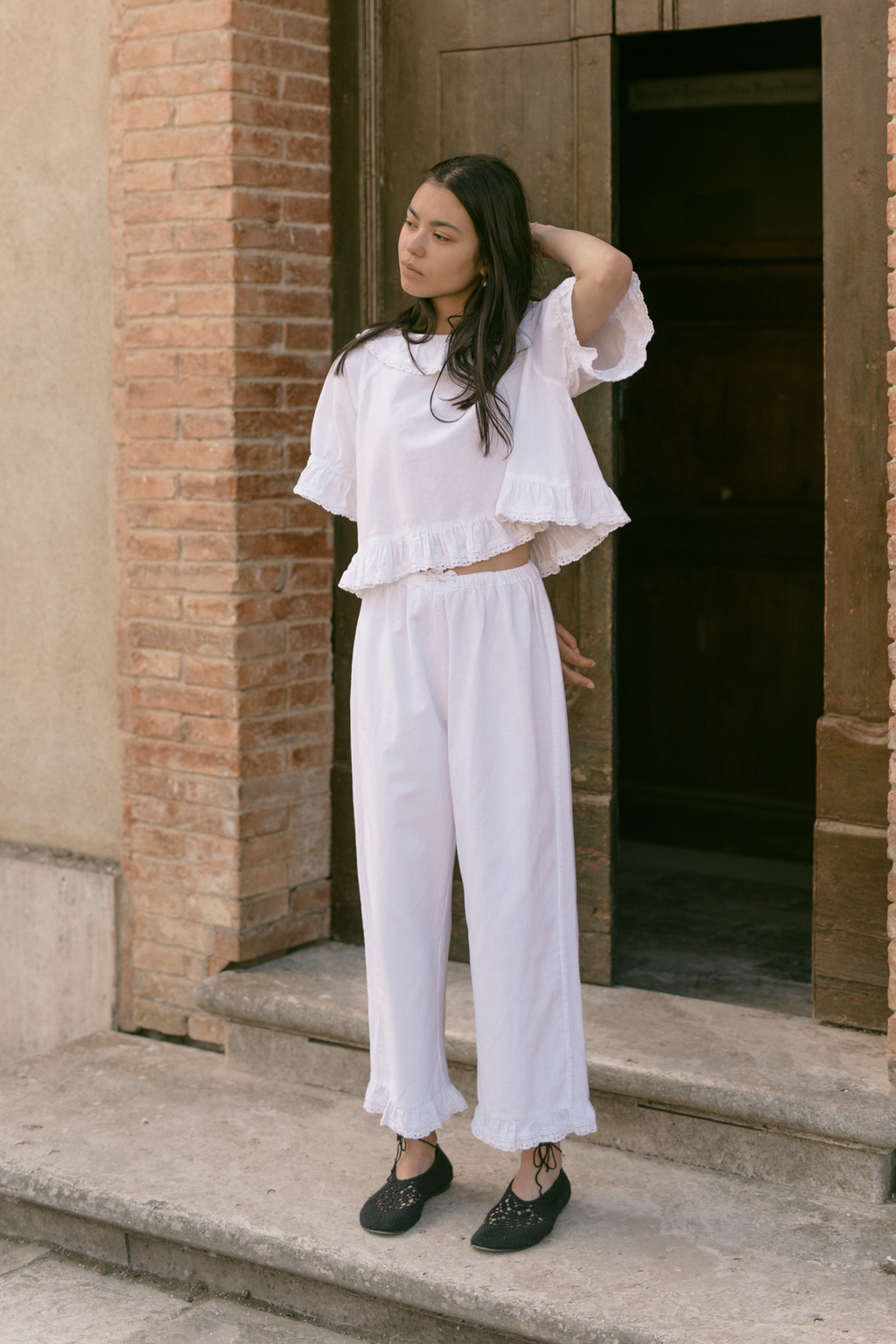 Model wearing the Arlette Pant in Salt by Gillian Stevens, full-length front view against a brick doorway