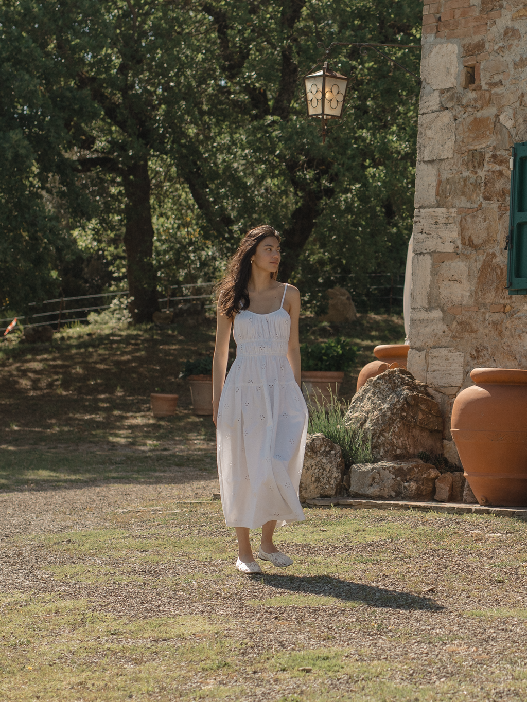 Model wearing the Alessandra Dress in Salt by Gillian Stevens, full-length front view in a sunlit stone courtyard