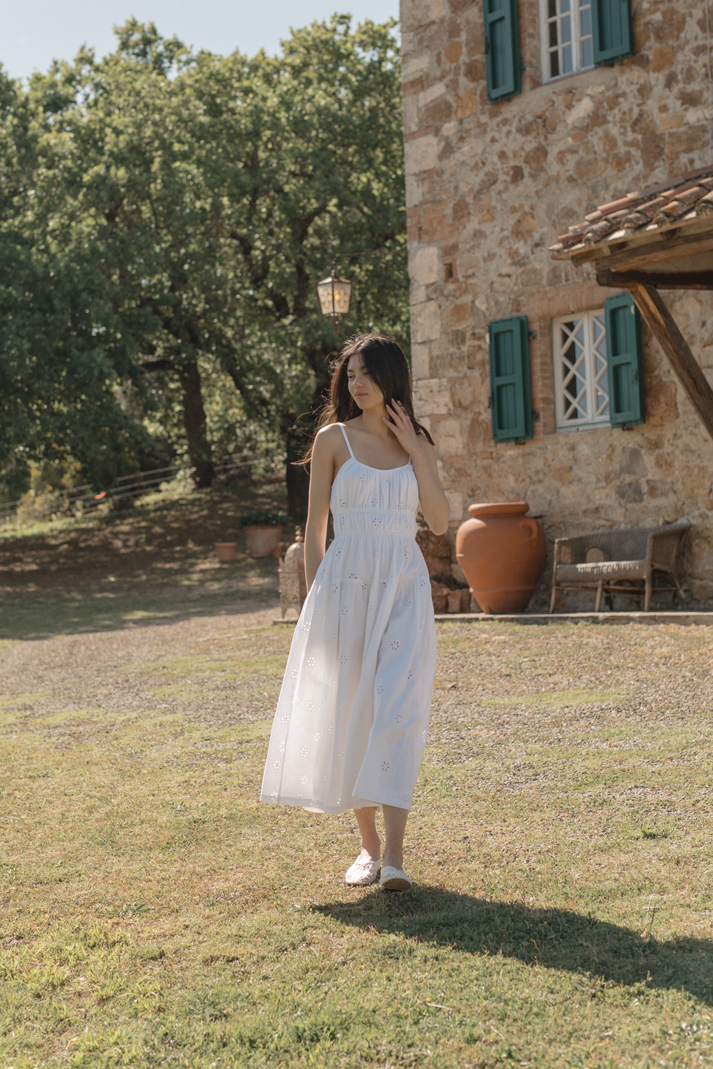 Model wearing the Alessandra Dress in Salt by Gillian Stevens, full-length front view outdoors at a Tuscan stone villa