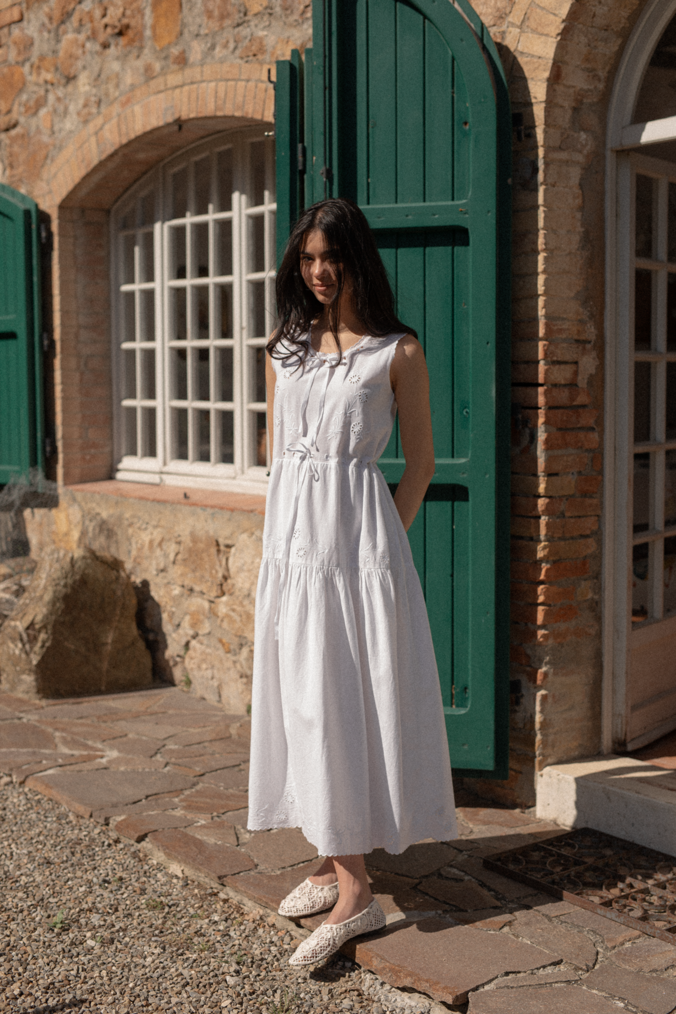 Model wearing the Plum Dress in Salt by Gillian Stevens, front view outside a stone building