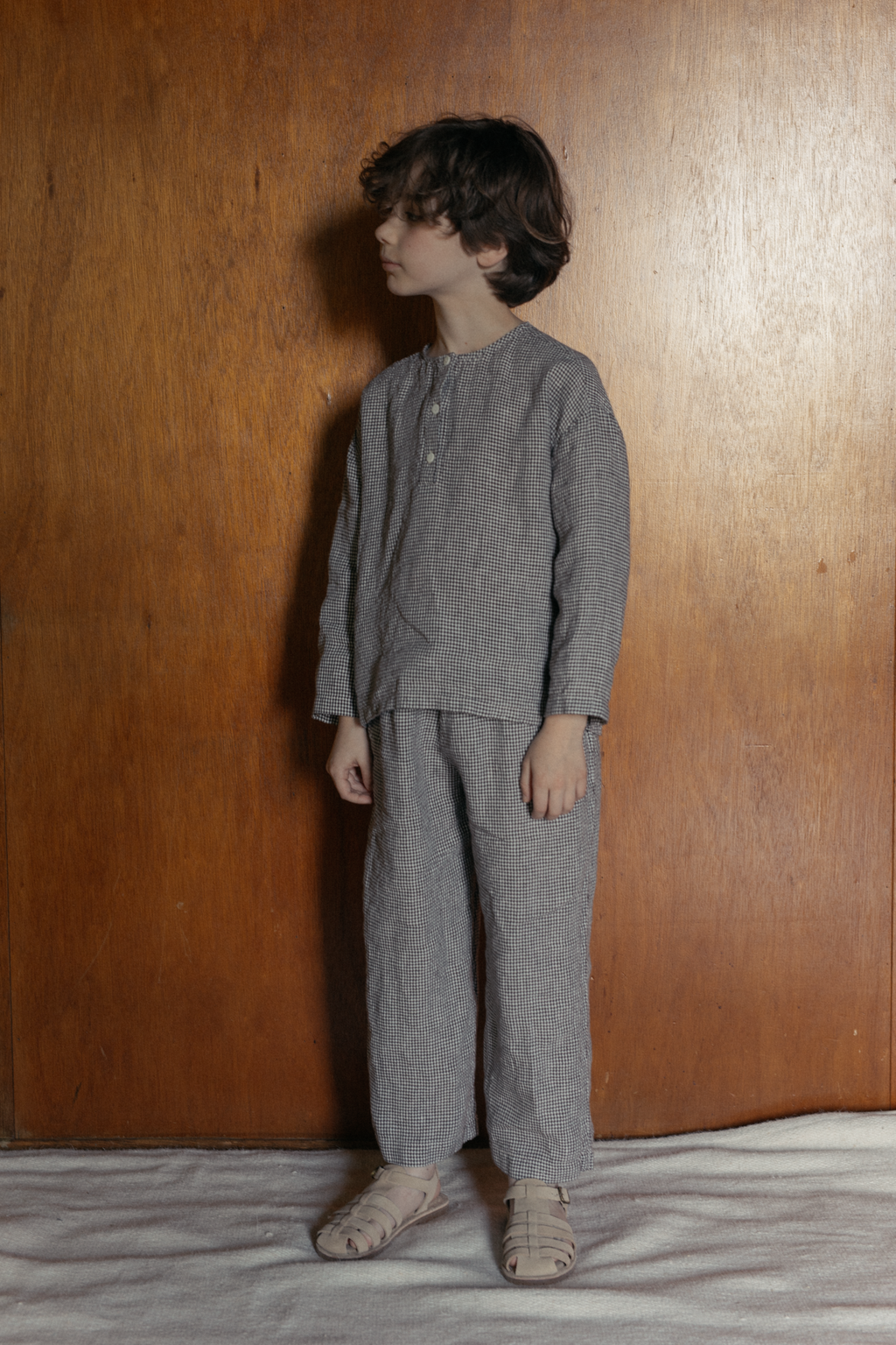 Child wearing the Bertie Top in Espresso Gingham by Gillian Stevens, side-front view styled with matching pants