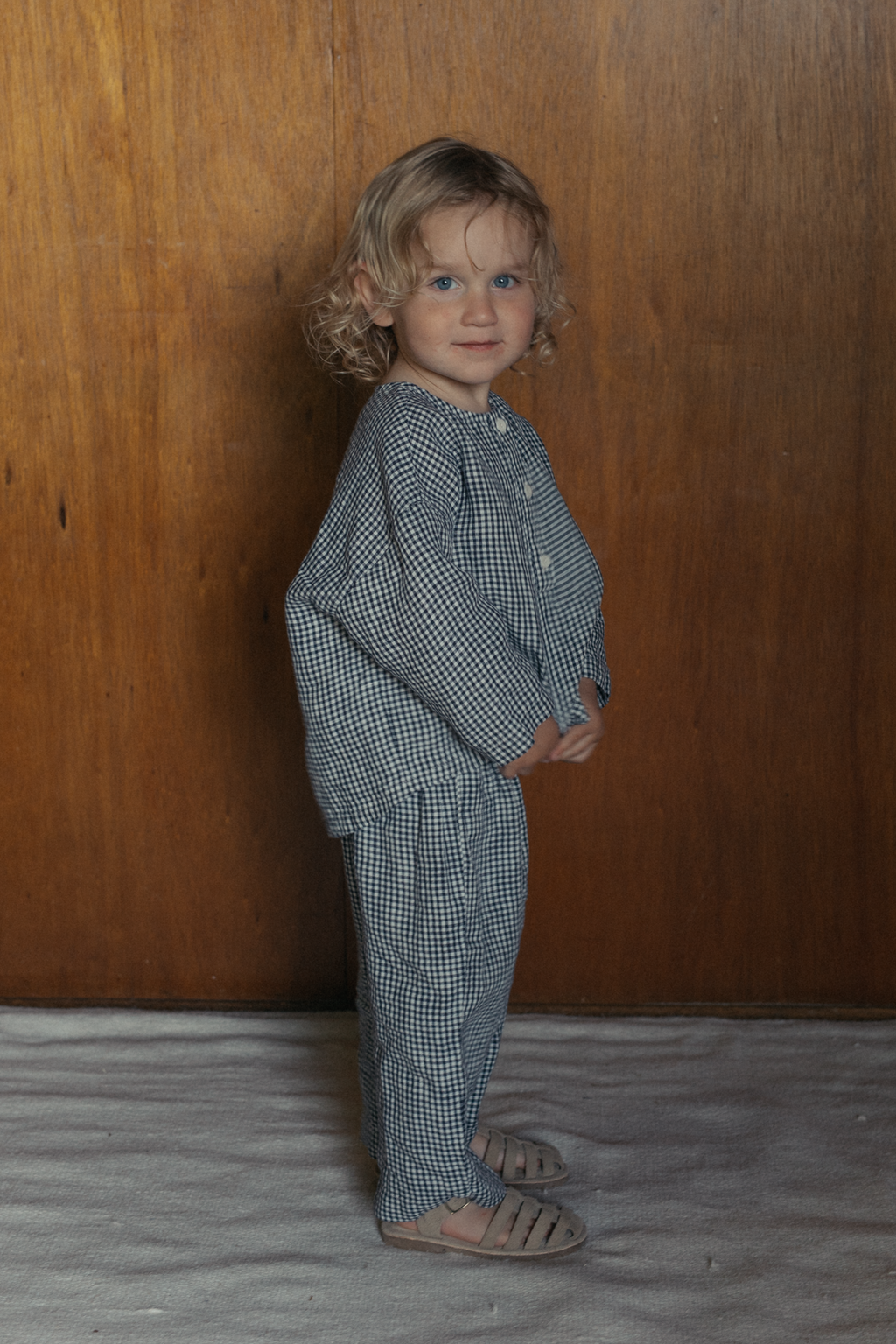 Child wearing the Bertie Top in Marine Gingham by Gillian Stevens, front view showing gingham check and long sleeves
