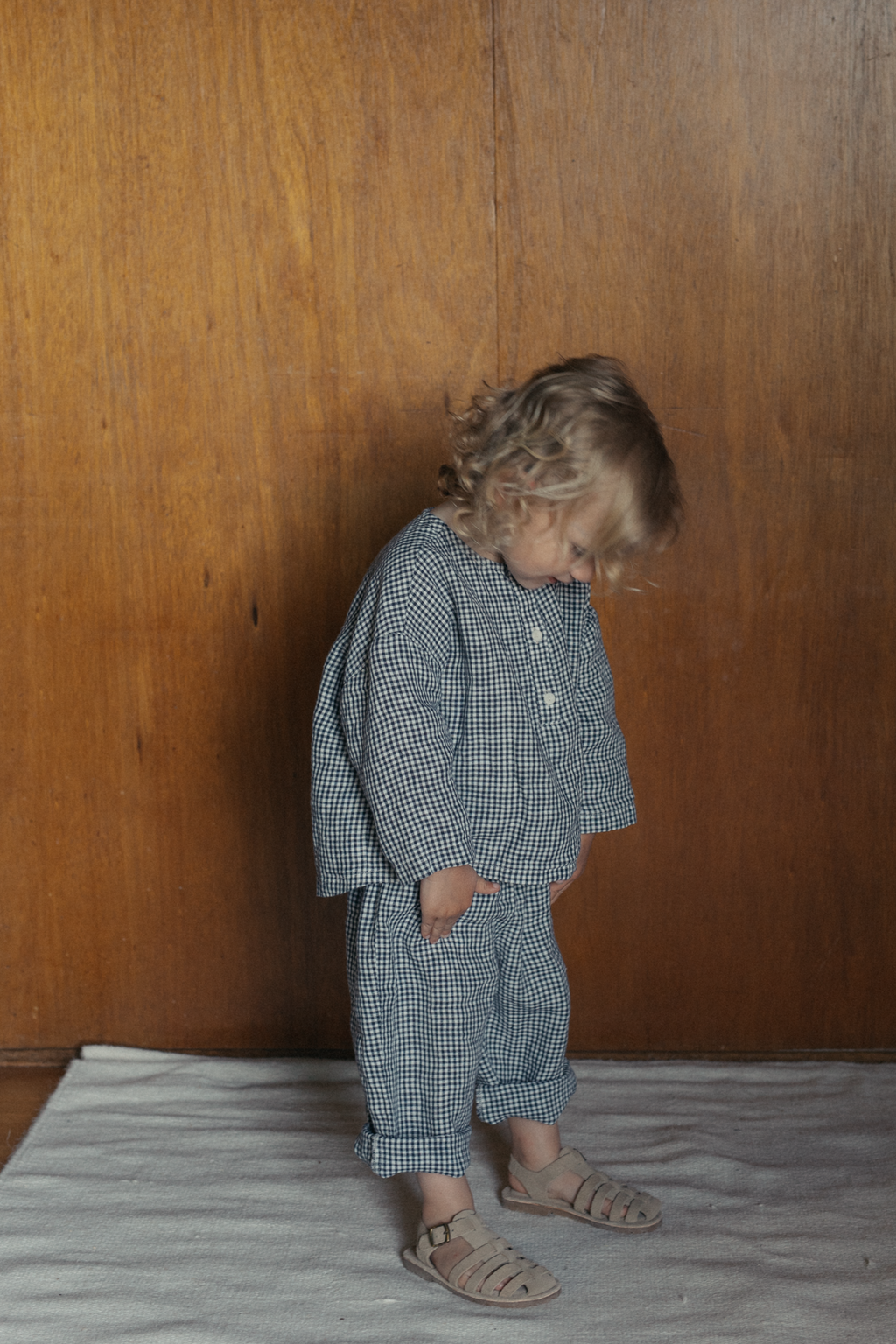 Child wearing the Bertie Top in Marine Gingham by Gillian Stevens, side view styled with matching pants