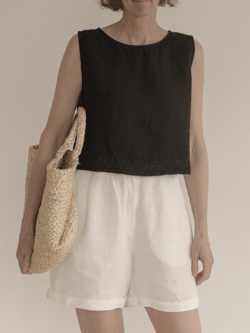 Model wearing the Finley Top in Noir by Gillian Stevens, front view styled with white shorts
