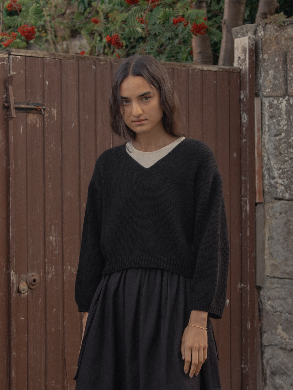 Model wearing the Lily Pullover in Noir by Gillian Stevens, front view in outdoor setting