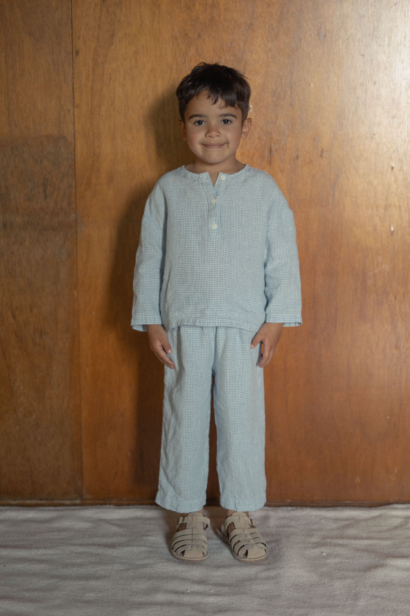 Child wearing the Bertie Top in Pale Blue Gingham by Gillian Stevens, front view styled with matching pants