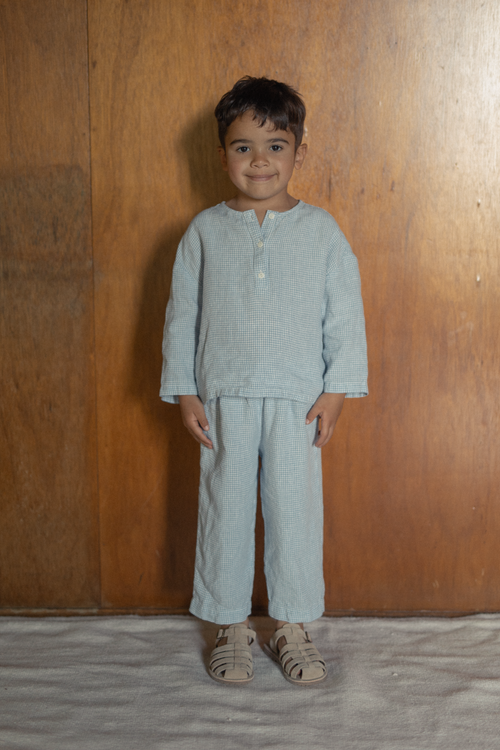 Child wearing the Bertie Top in Pale Blue Gingham by Gillian Stevens, front view styled with matching pants