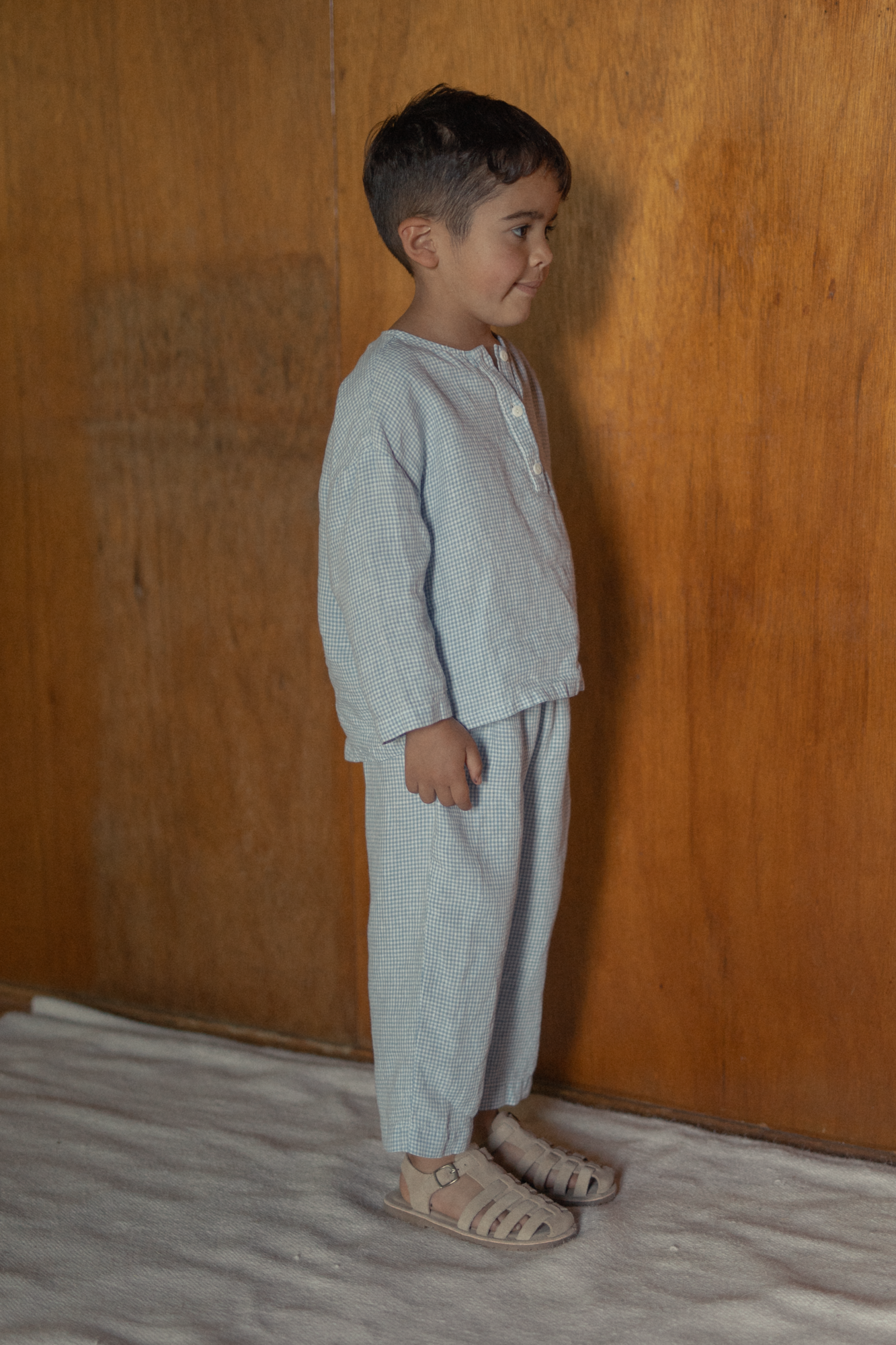 Child wearing the Bertie Pant in Pale Blue Gingham by Gillian Stevens, side view showing tapered leg and elasticated waist