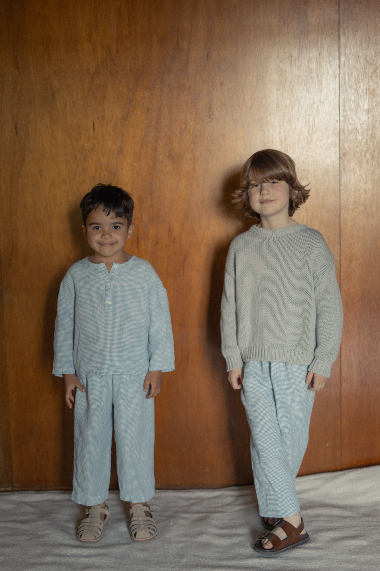 Child wearing the Mini Townes Pullover in Pebble by Gillian Stevens, front view styled with check pants