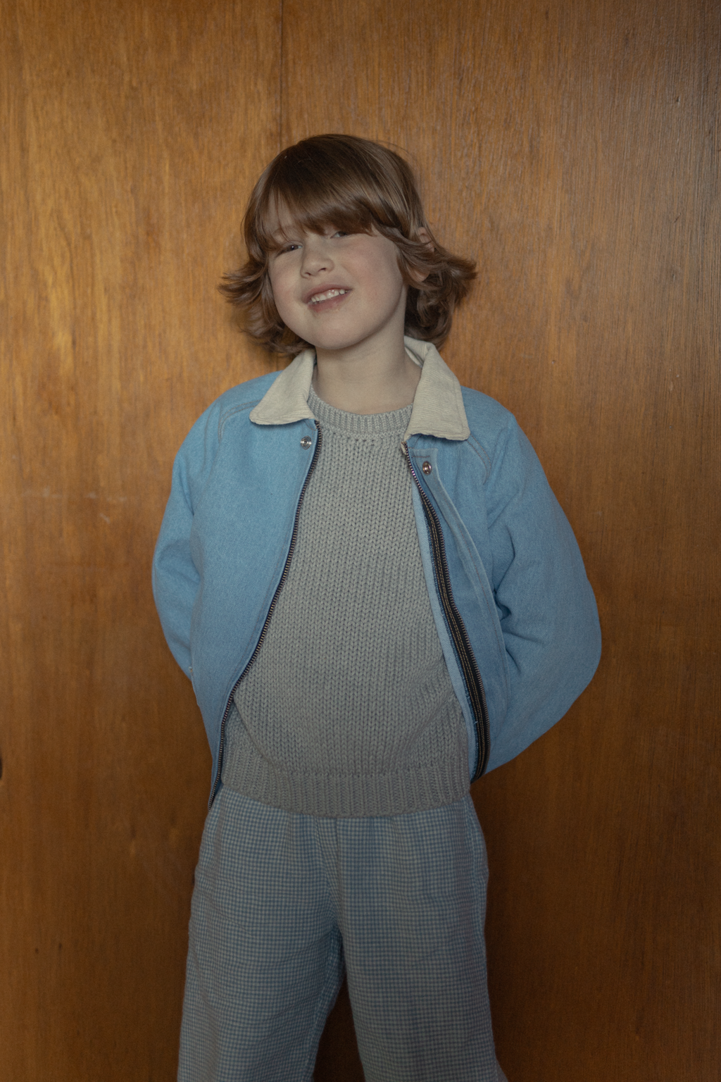Child wearing the Brooks Jacket in Vintage Blue by Gillian Stevens, front view styled over a knit sweater