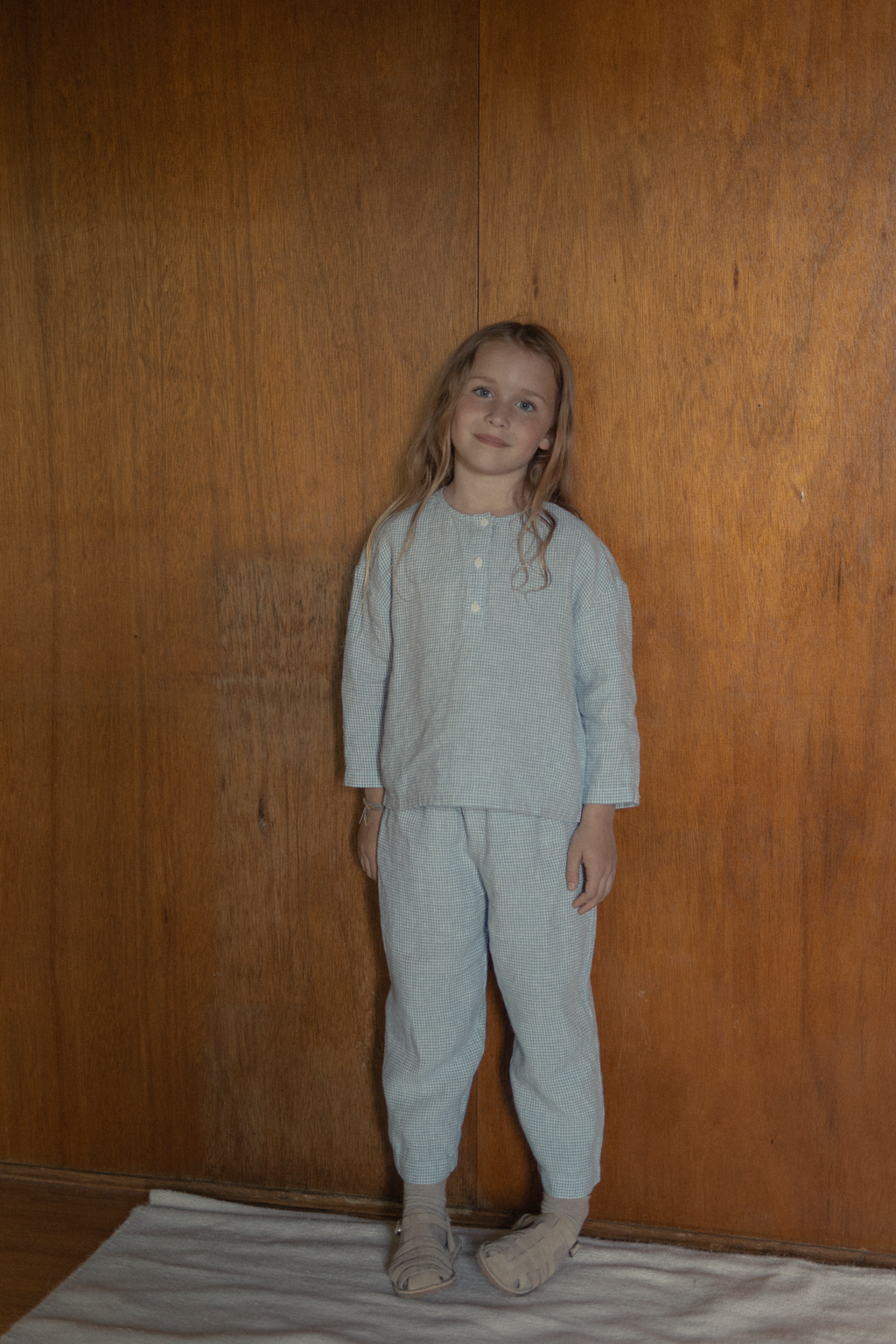 Child wearing the Bertie Pant in Pale Blue Gingham by Gillian Stevens, front view styled with matching top