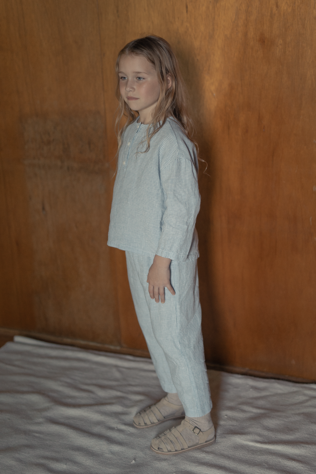 Child wearing the Bertie Pant in Pale Blue Gingham by Gillian Stevens, side view showing tapered leg