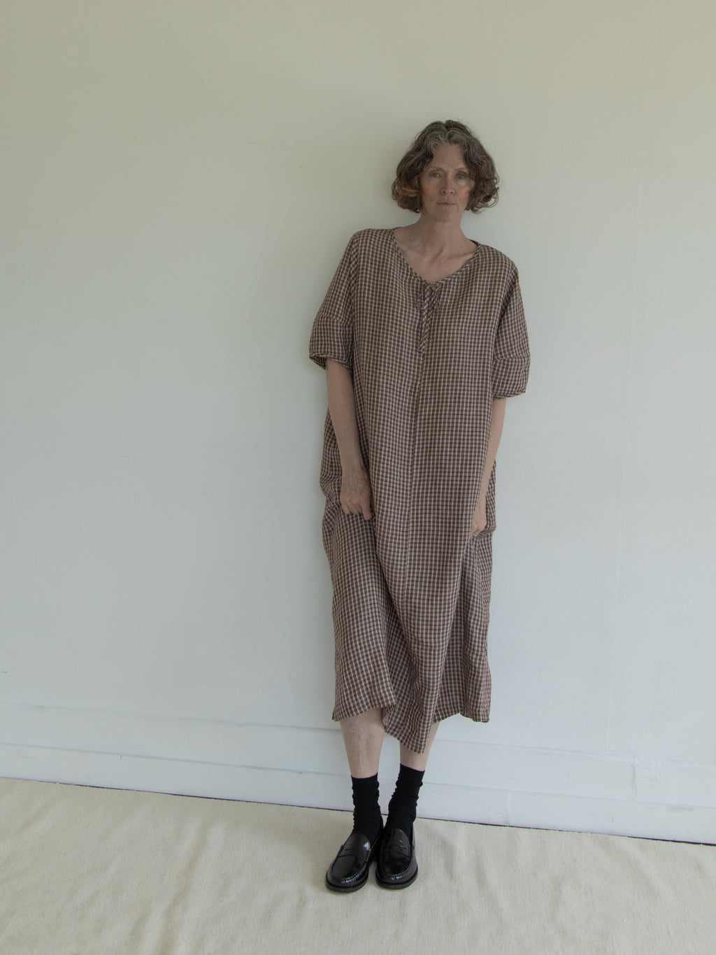 Model wearing the Blair Dress in Chocolate Plaid by Gillian Stevens, front view showing relaxed silhouette and side pockets